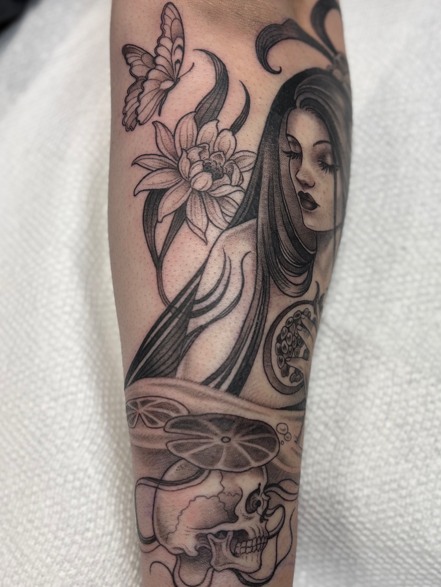 Woman with lotus and skull realism tattoo on the forearm by Kinsey Miller