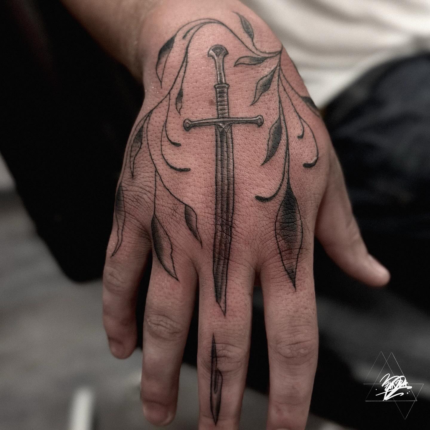 Sword and leaves black and grey tattoo on the hand by Zhorana Devi