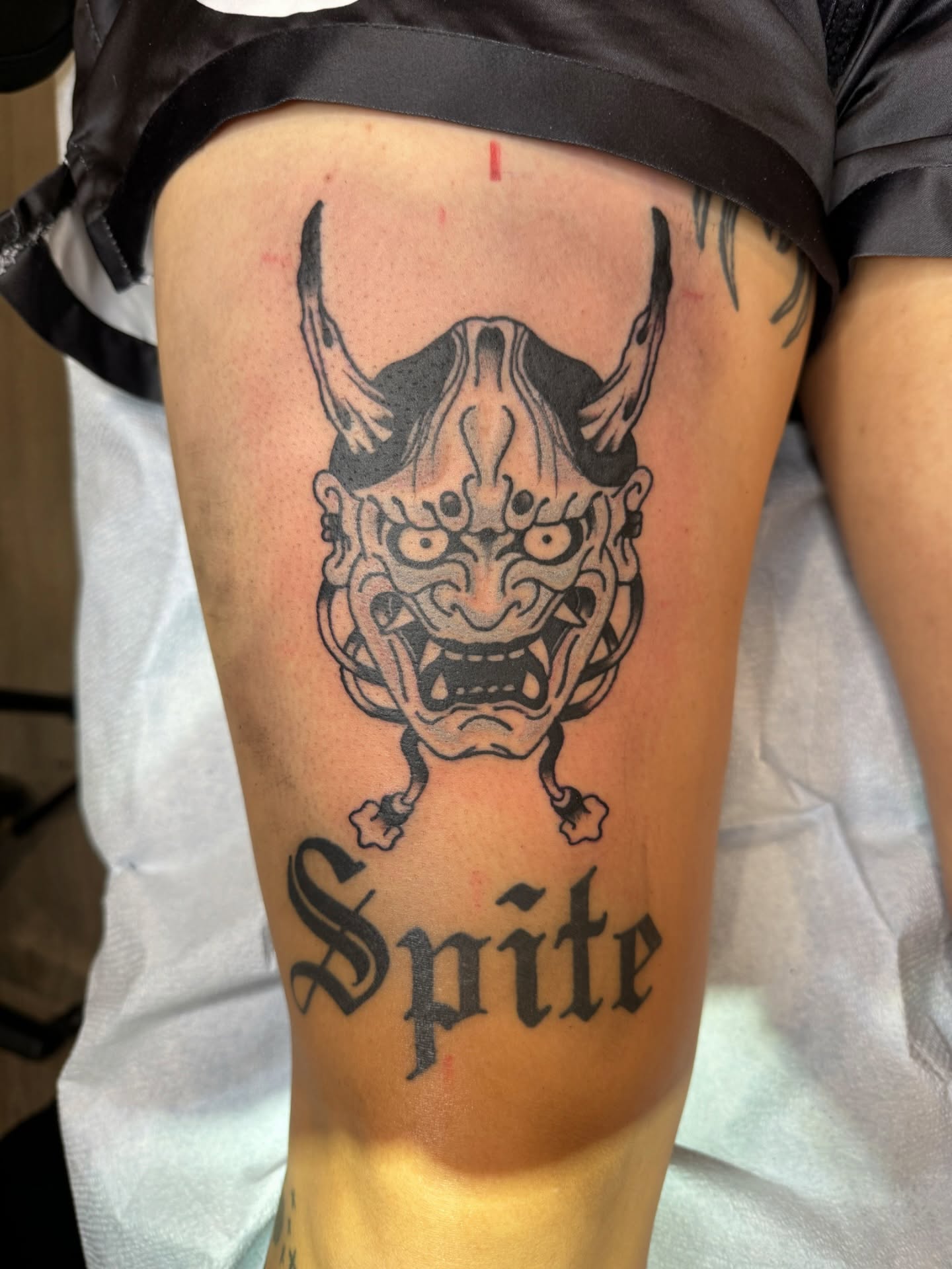 Demon mask black and grey tattoo on the thigh by Minneapolis
