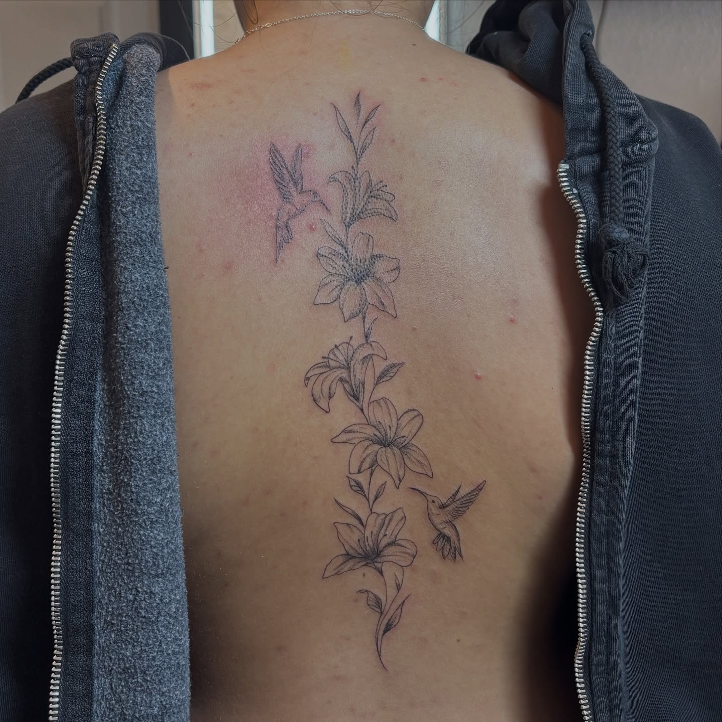 Lilies and hummingbirds black and grey tattoo on the back by Sydney Gallucci