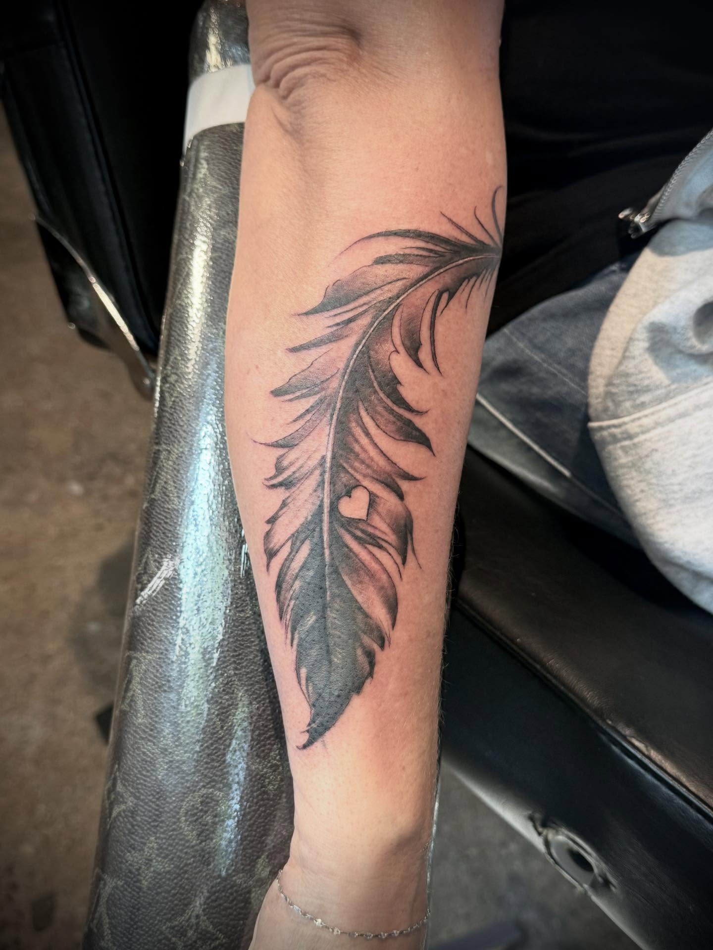 Feather black and grey tattoo on the forearm by Matthew Crawley