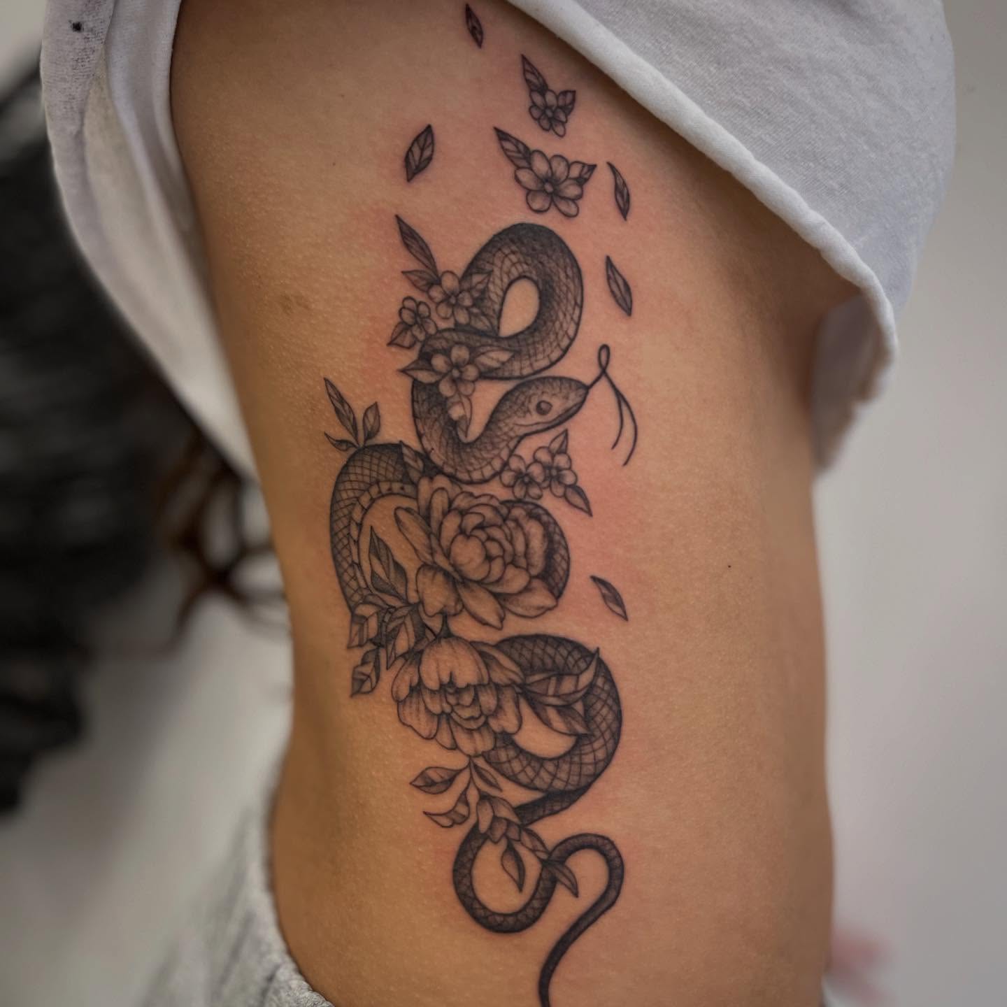 Snake and flowers ornamental tattoo on the thigh by Miesha Busker
