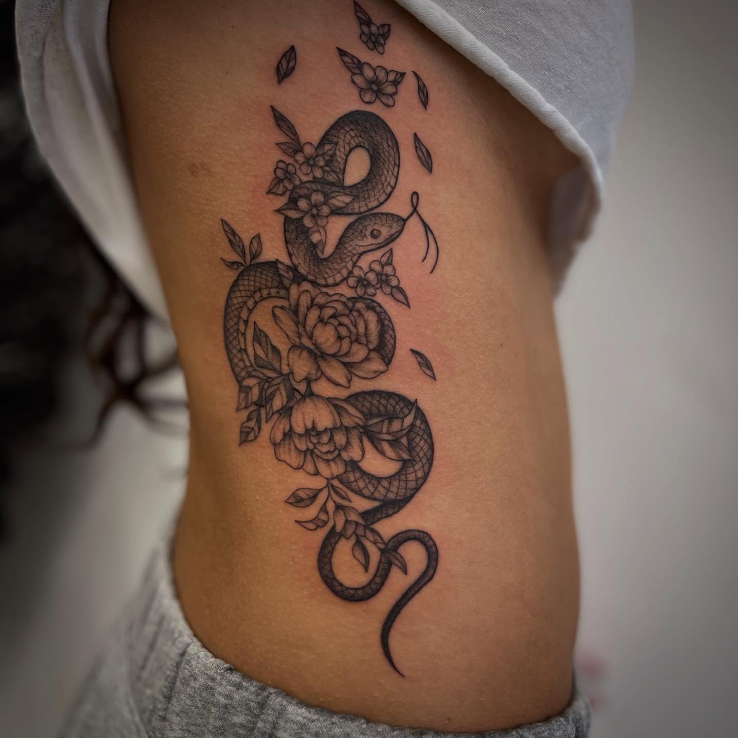 Snake and flowers ornamental tattoo on the ribs by Miesha Busker