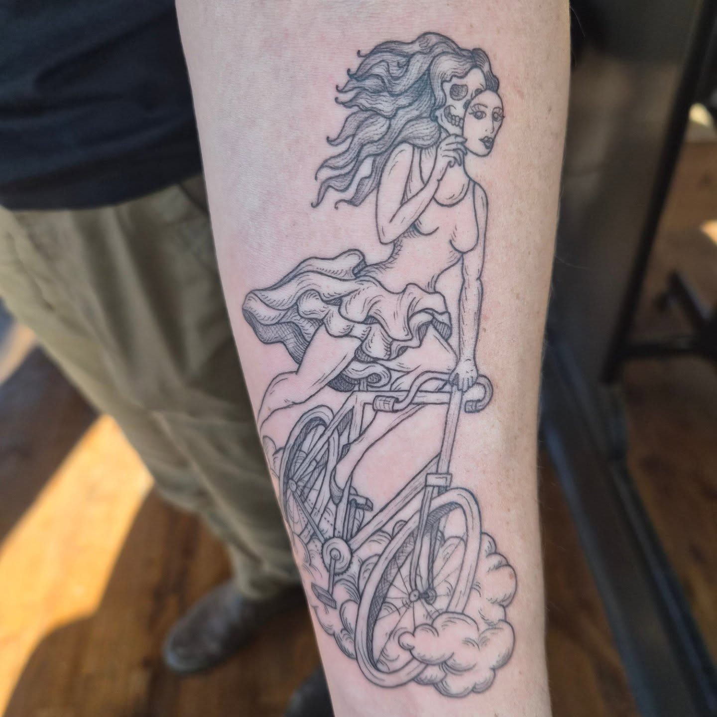 Woman on bicycle realism tattoo on the forearm by Lora Bird