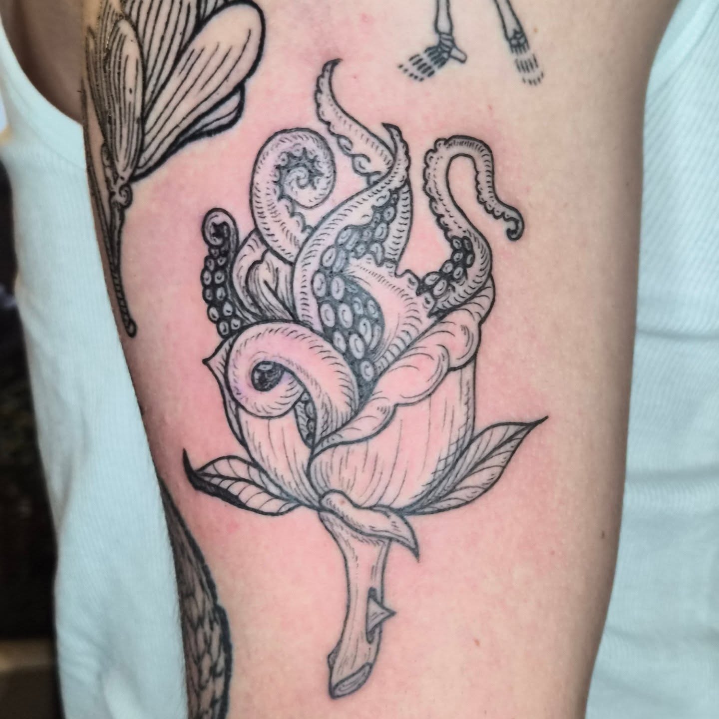 Octopus in rose realism tattoo on the forearm by Lora Bird