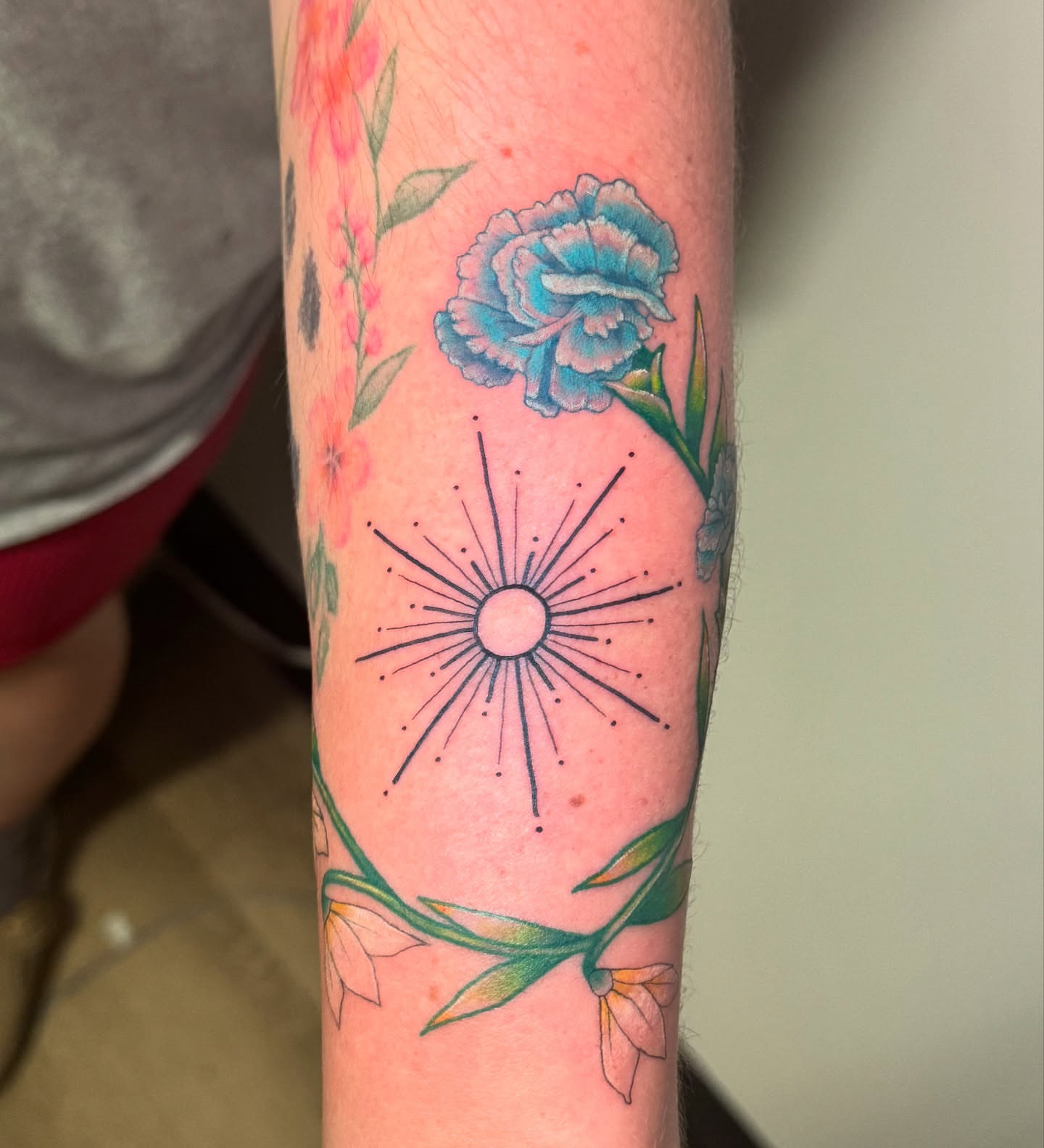 Sun and flowers dotwork tattoo on the forearm by Madison Pegram