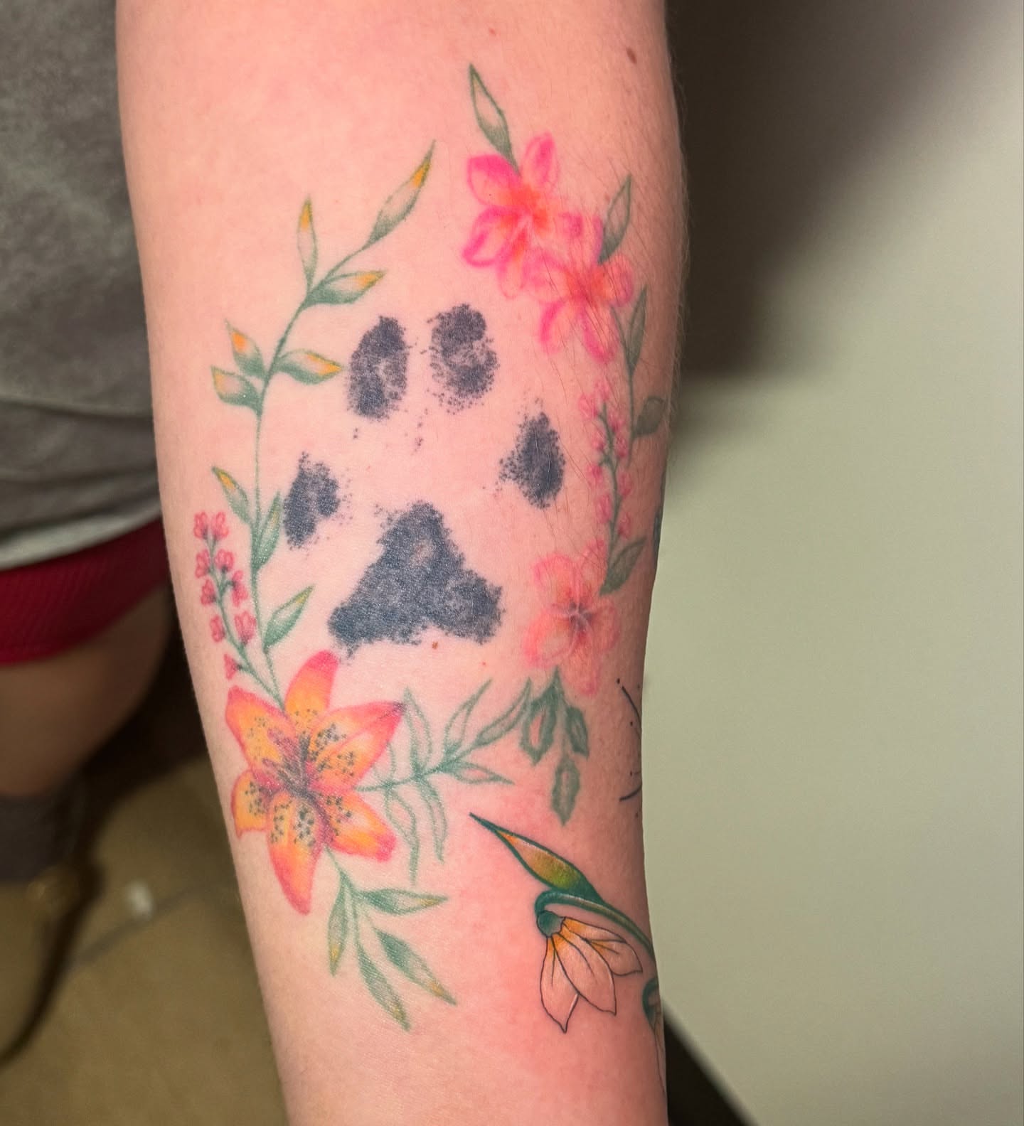 Paw print with floral design dotwork tattoo on the forearm by Madison Pegram