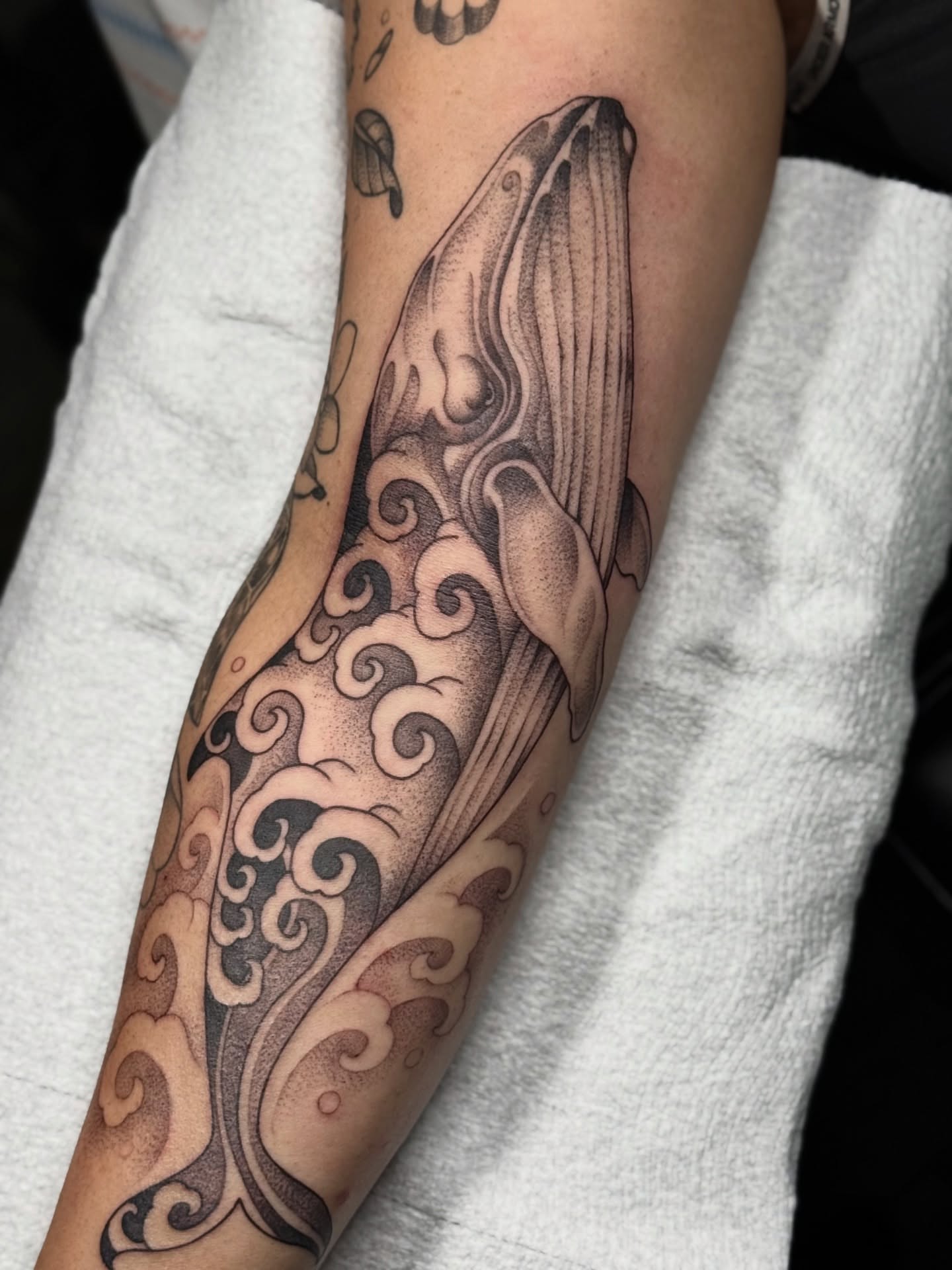 Whale and waves dotwork tattoo on the forearm by Miles Romero Smith