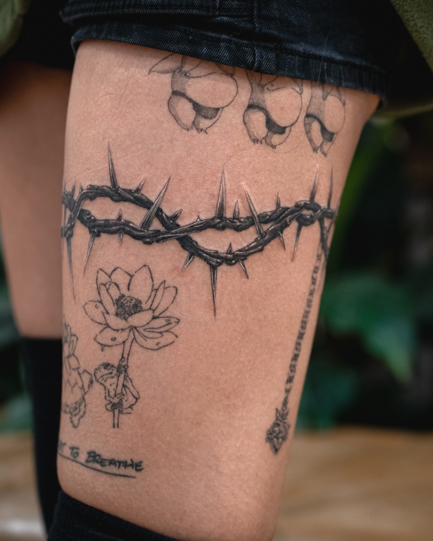 Crown of thorns and lotus flower black and grey tattoo on the thigh by James Fernella, San Francisco, California