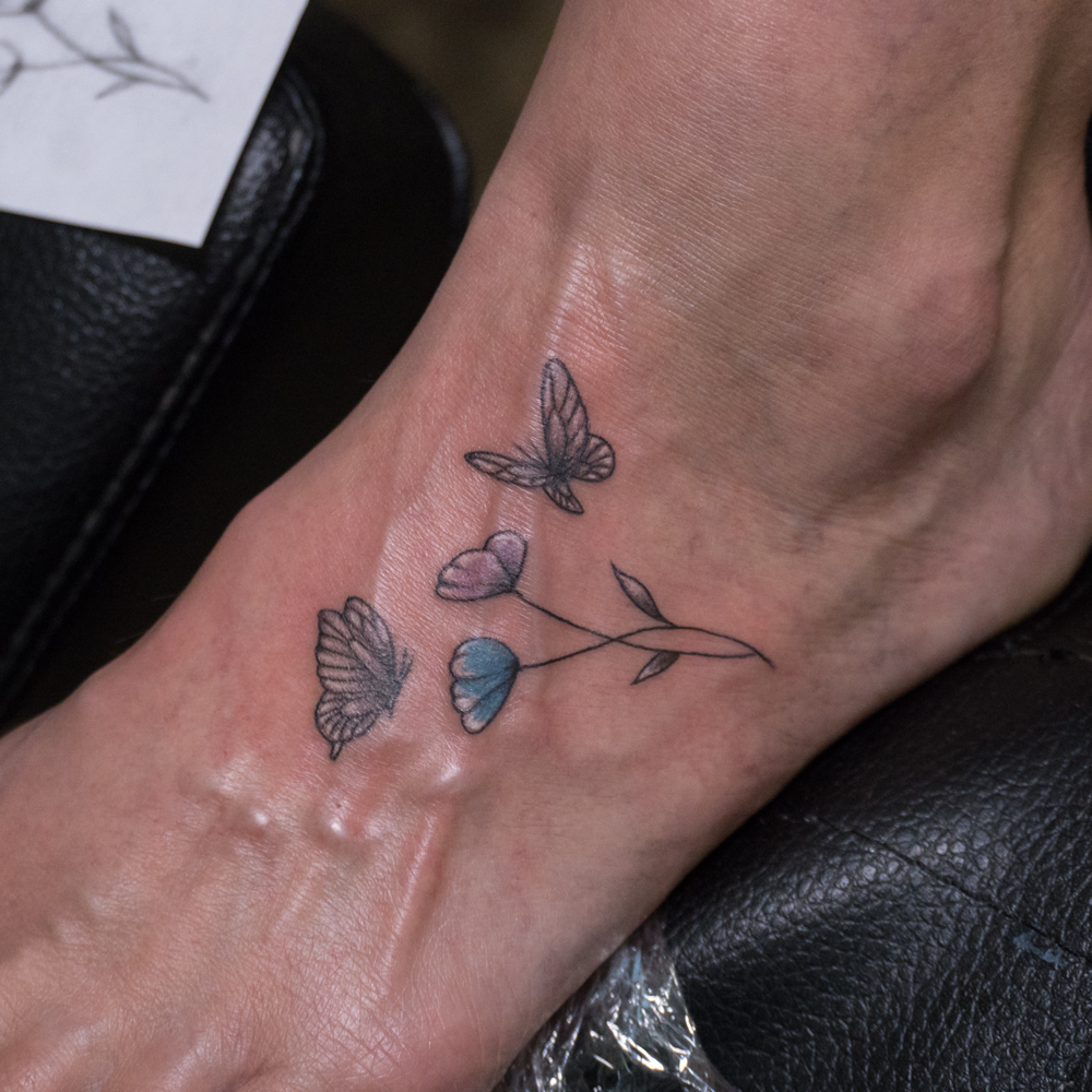 Butterfly and flowers dotwork tattoo on the foot by Donald Voelker
