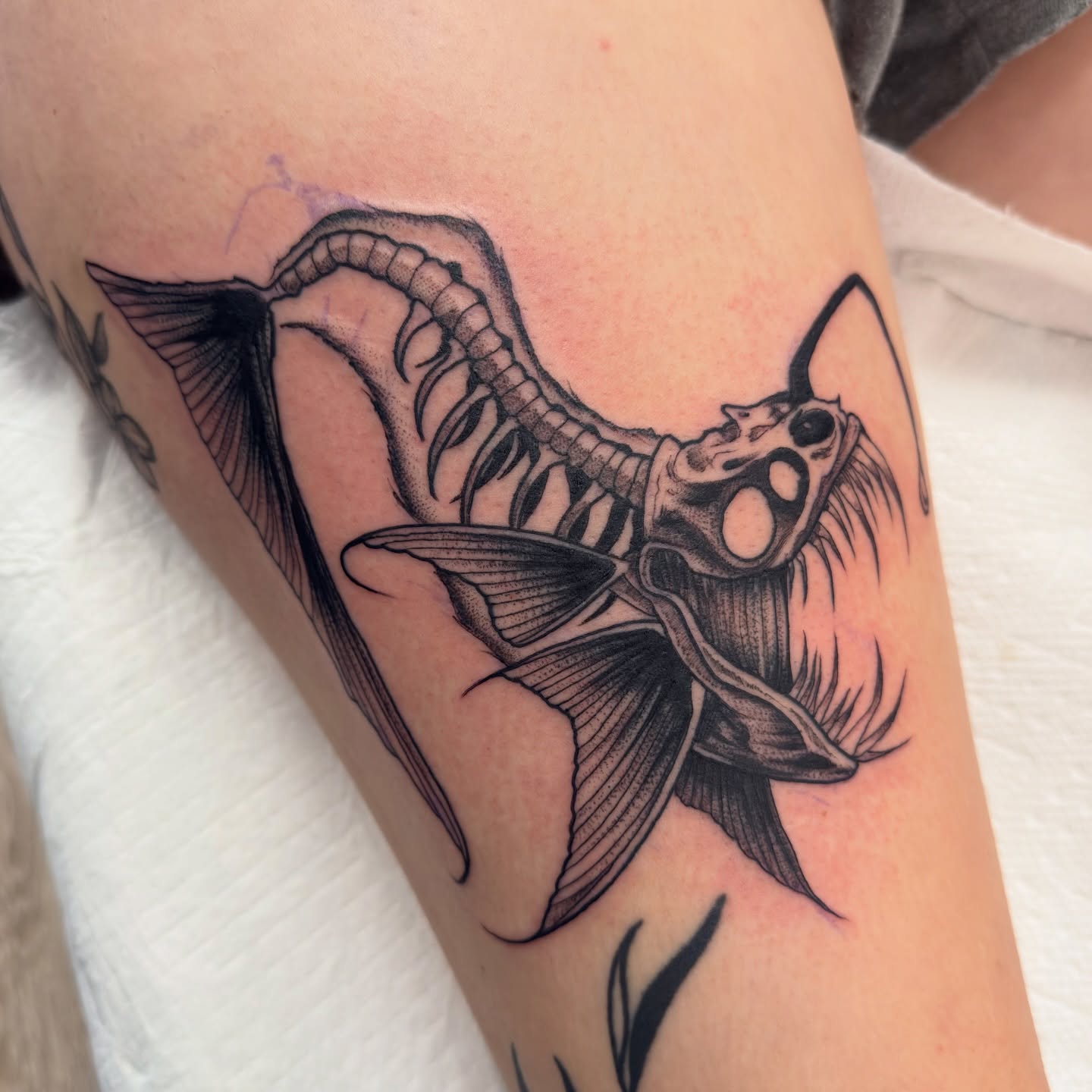 Fish skeleton black and grey tattoo on the forearm by Justin Hay