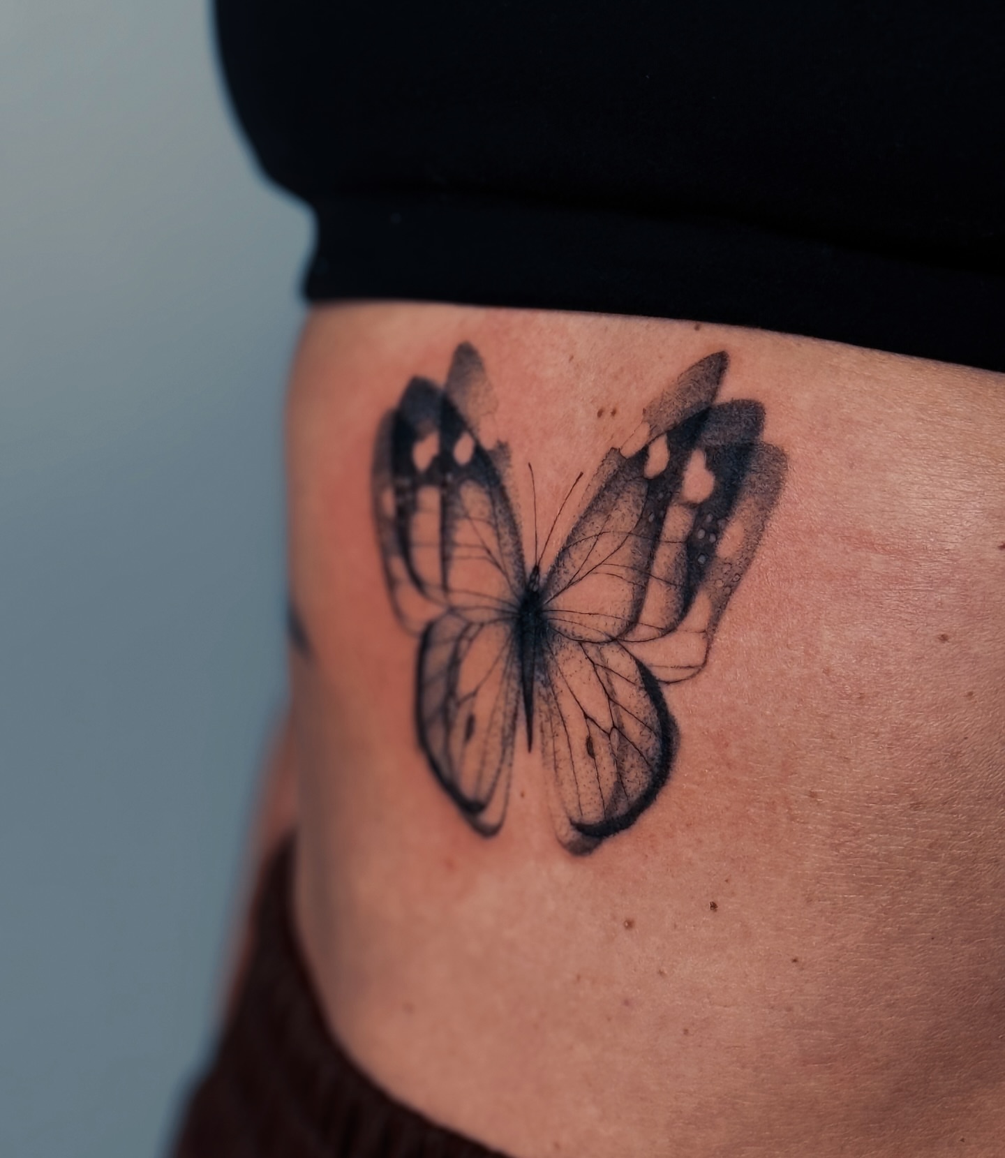 Butterfly black and grey tattoo on the thigh by Olha Tytarenko