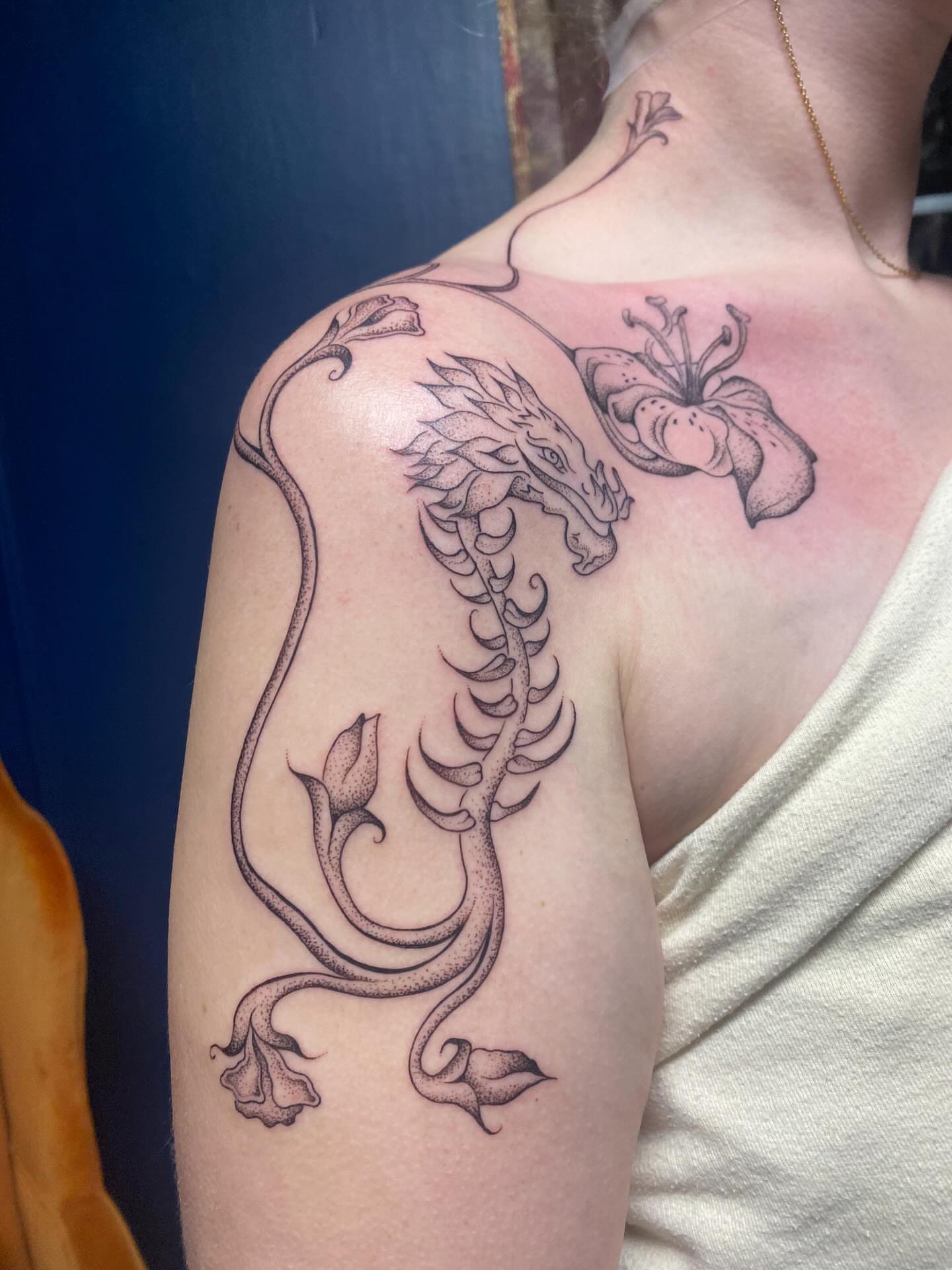 Dragon and lily black and grey tattoo on the shoulder by Jesikah Rapp