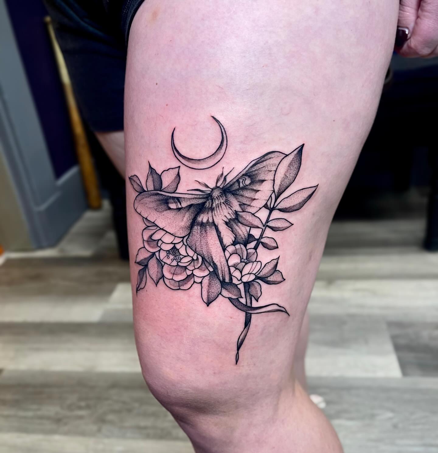 Moth and flowers realism tattoo on the thigh by Emily