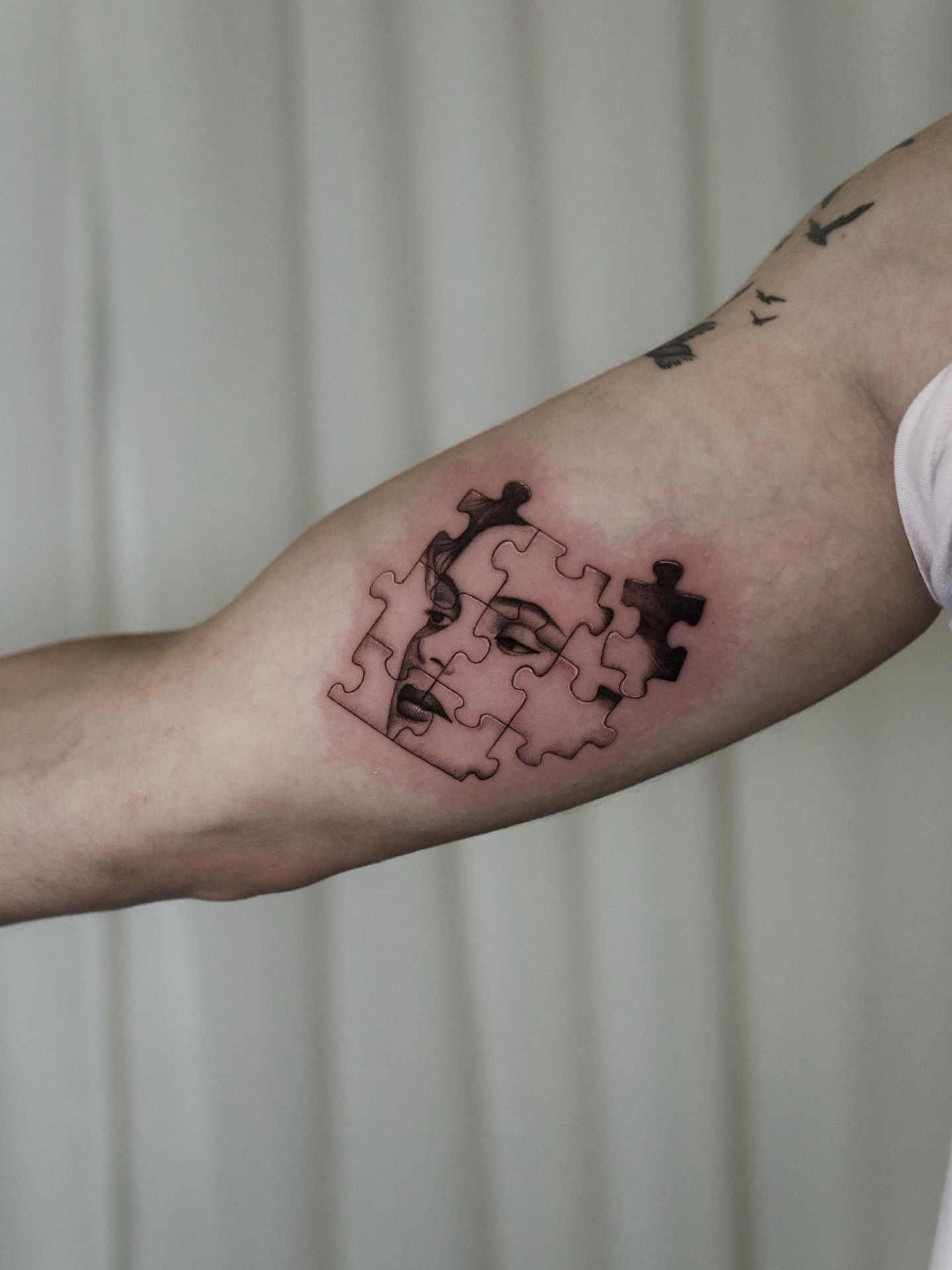 Puzzle piece black and grey tattoo on the forearm by Ray Quinday