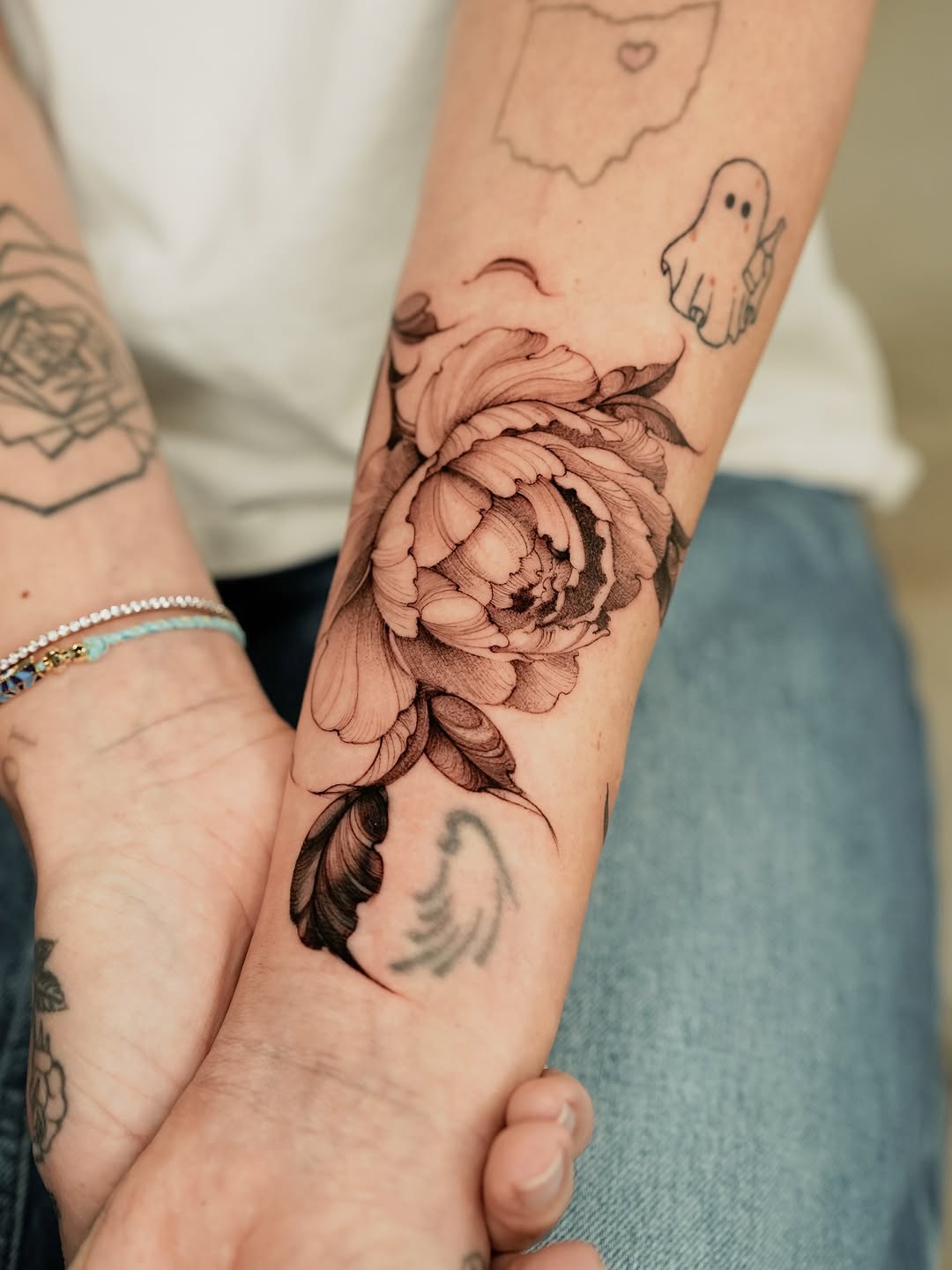 Peony and feather fine line tattoo on the forearm by Valentina
