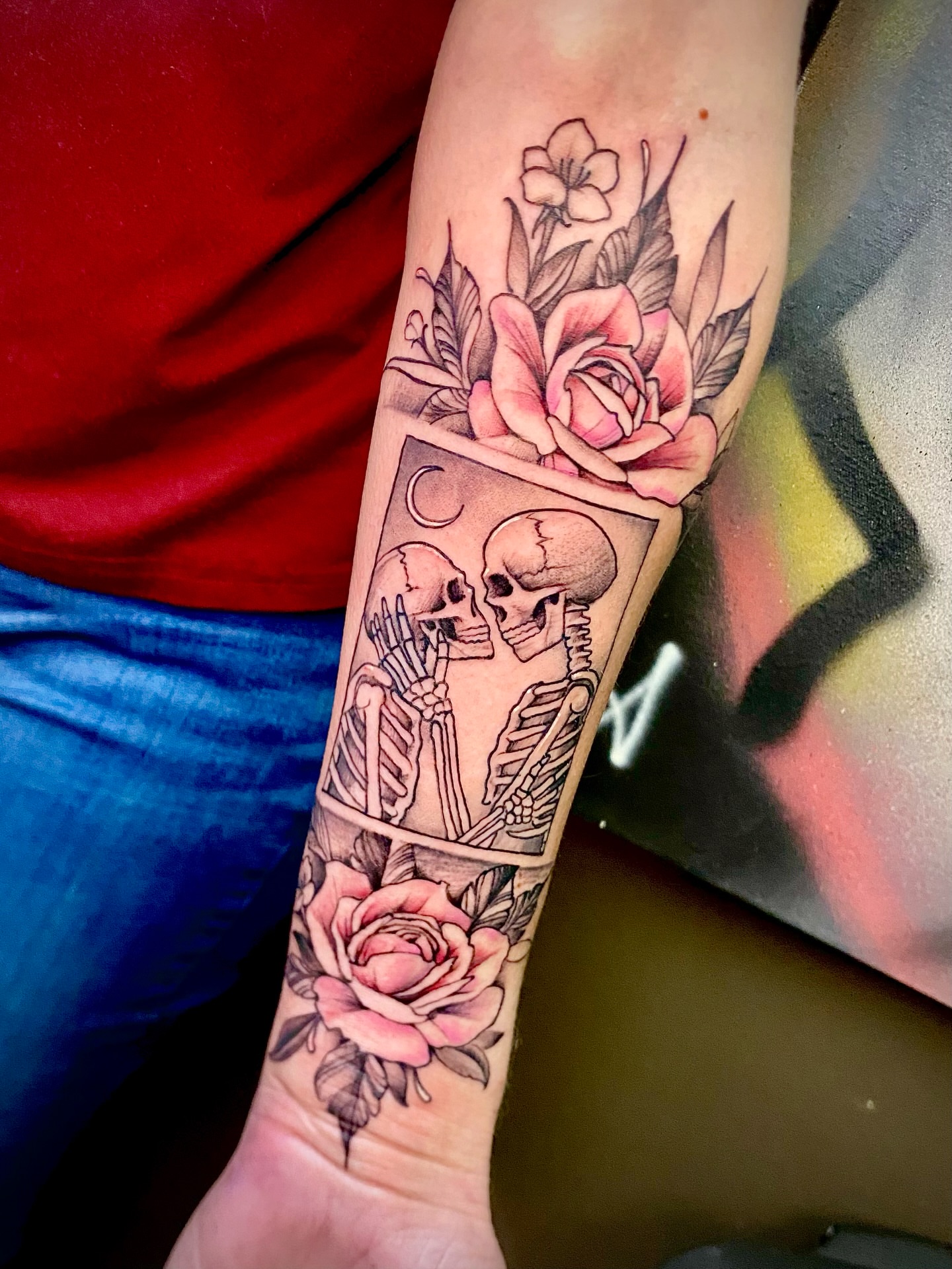 Skeletons and roses American traditional tattoo on the forearm by Adam Newton