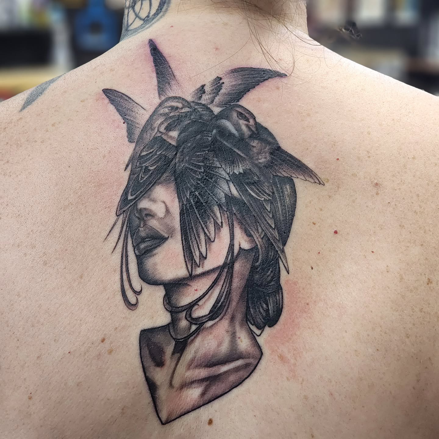 Woman with bird realism tattoo on the back by Robert Glover