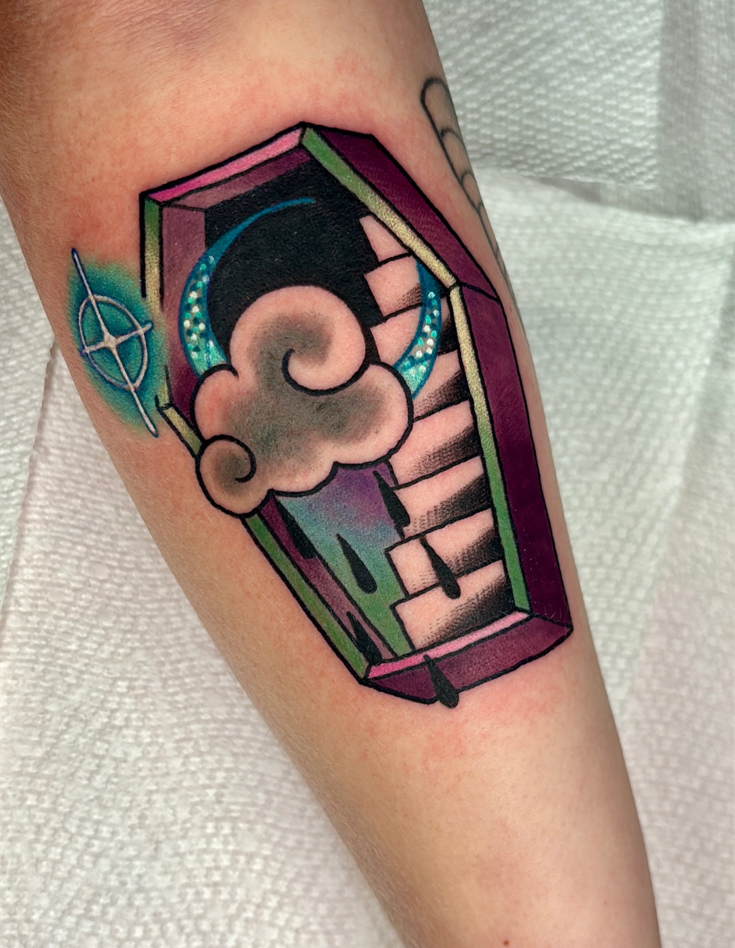 Casket with smoke new school tattoo on the forearm by Latesha Burnley