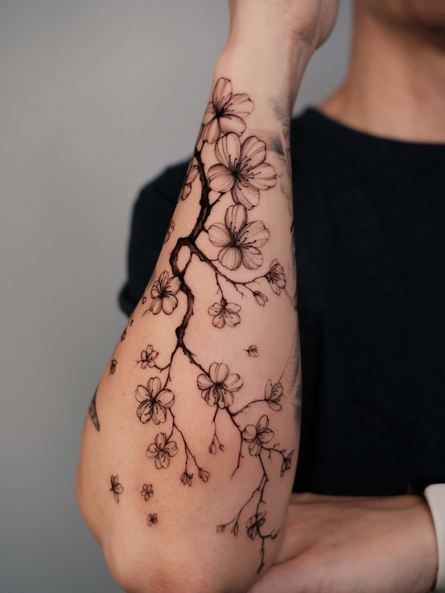 Cherry blossom branch black and grey tattoo on the forearm by Anastasiia