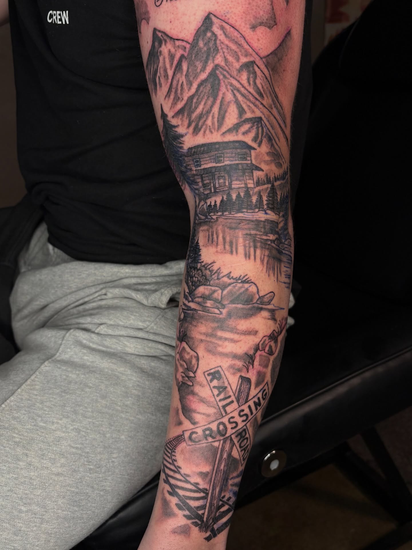 Mountain cabin landscape realism tattoo on the forearm by Evan Chastain
