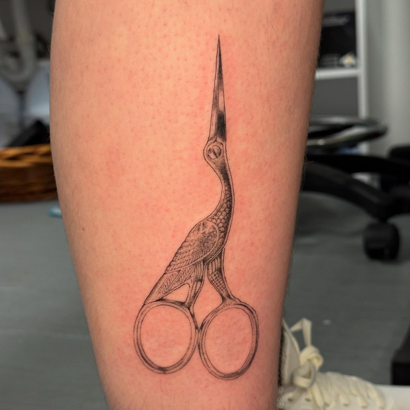 Scissors and crane black and grey tattoo on the forearm by Ivy