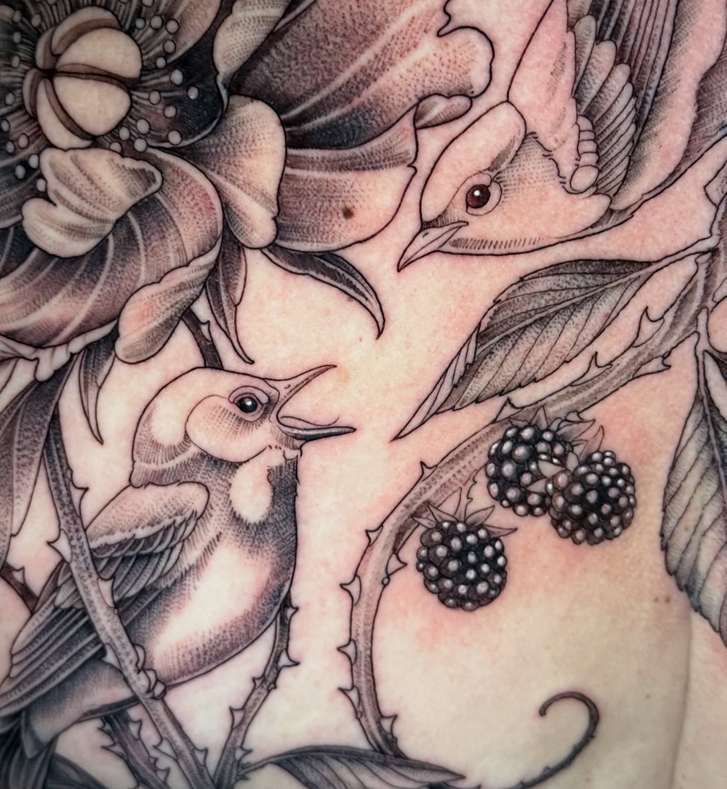 Birds and flowers realism tattoo on the chest by Lydia Jude