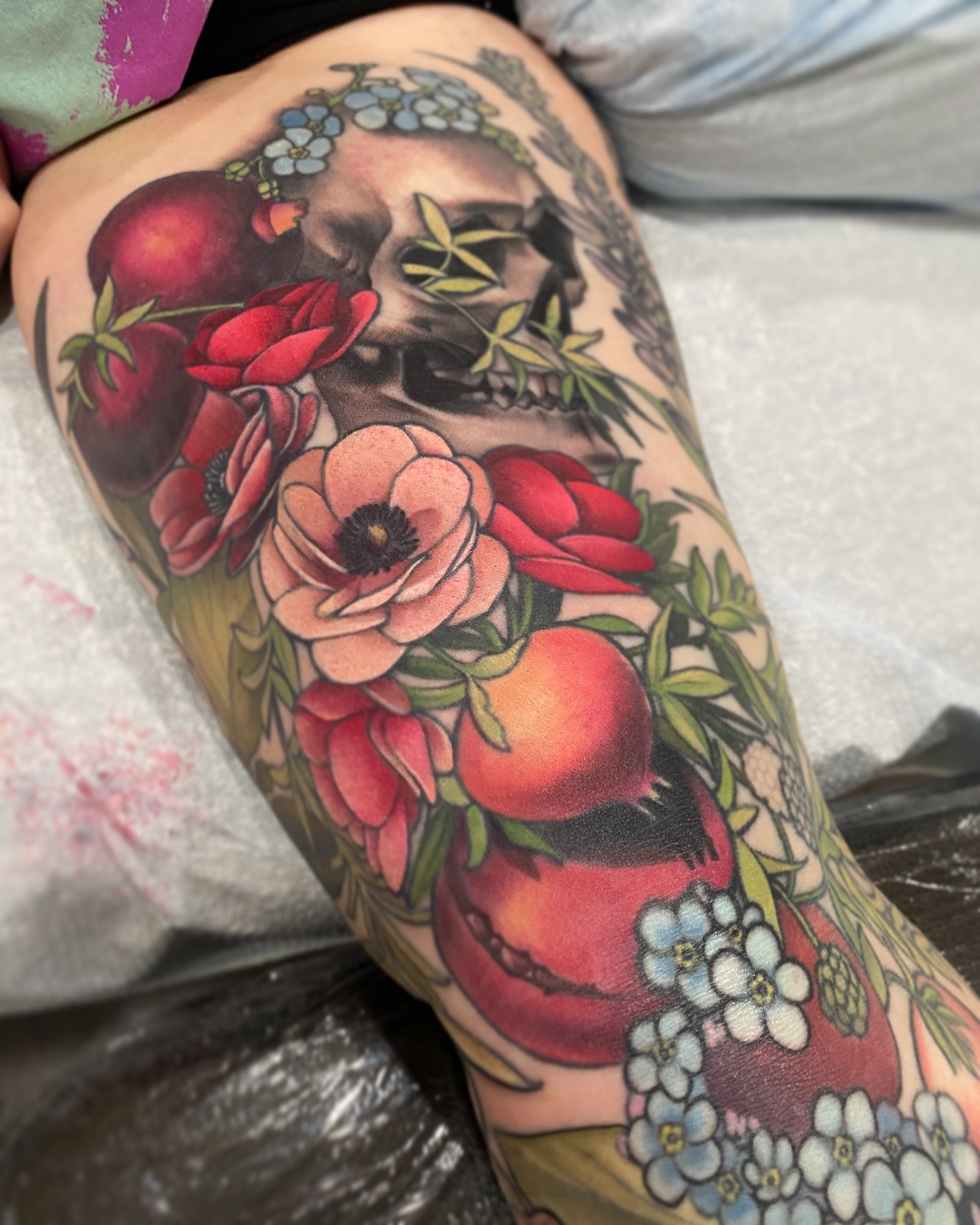 Skull and floral arrangement American traditional tattoo on the thigh by Anali De Laney