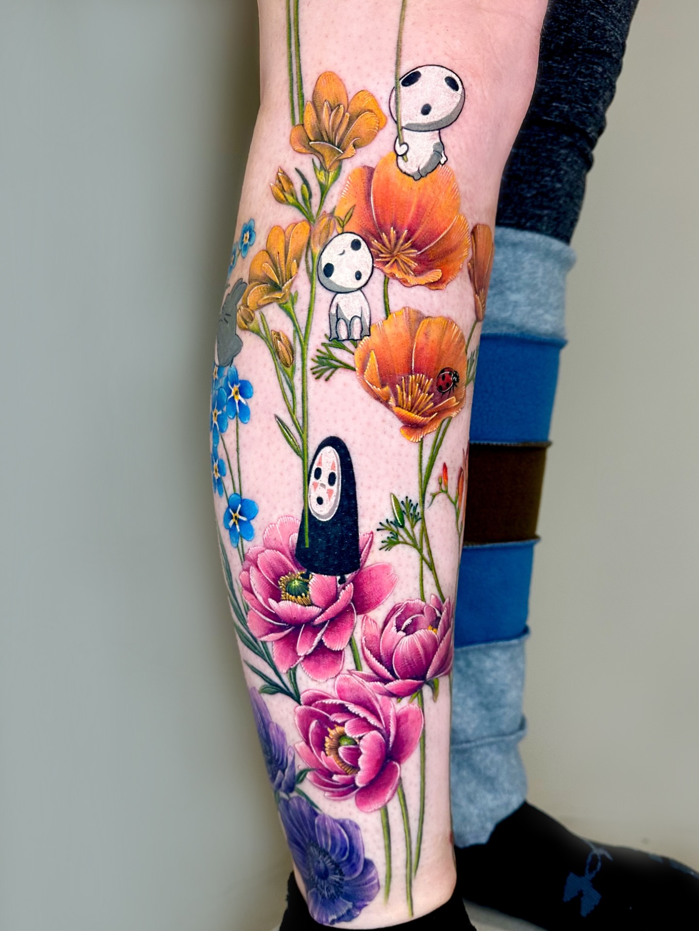 Flowers and spirits anime tattoo on the calf by Claire