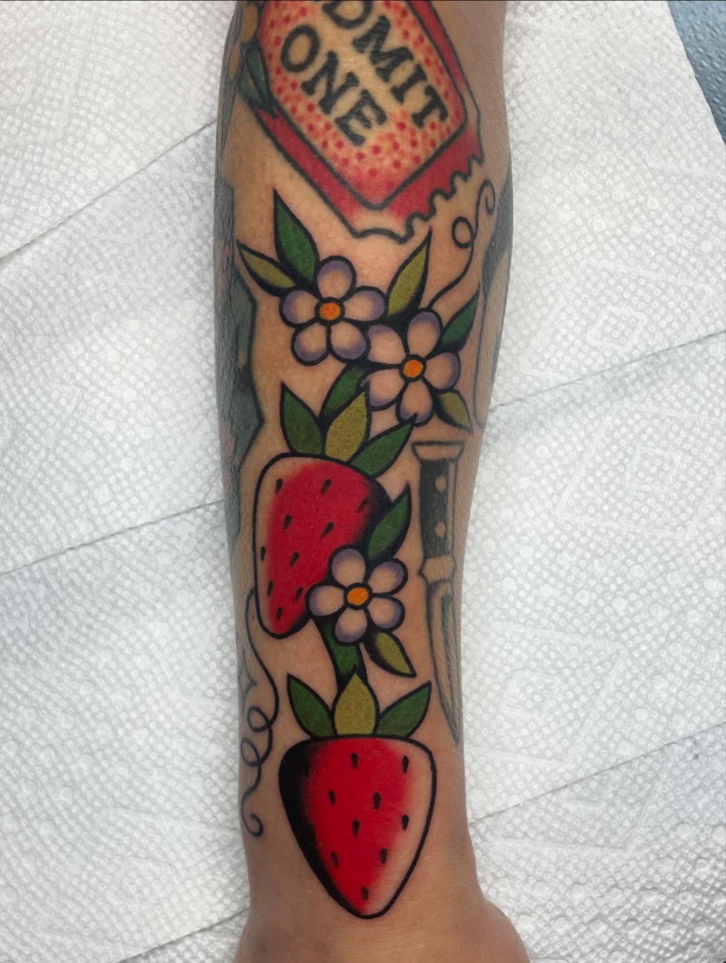 Strawberries and flowers American traditional tattoo on the forearm by Nova Vaughn