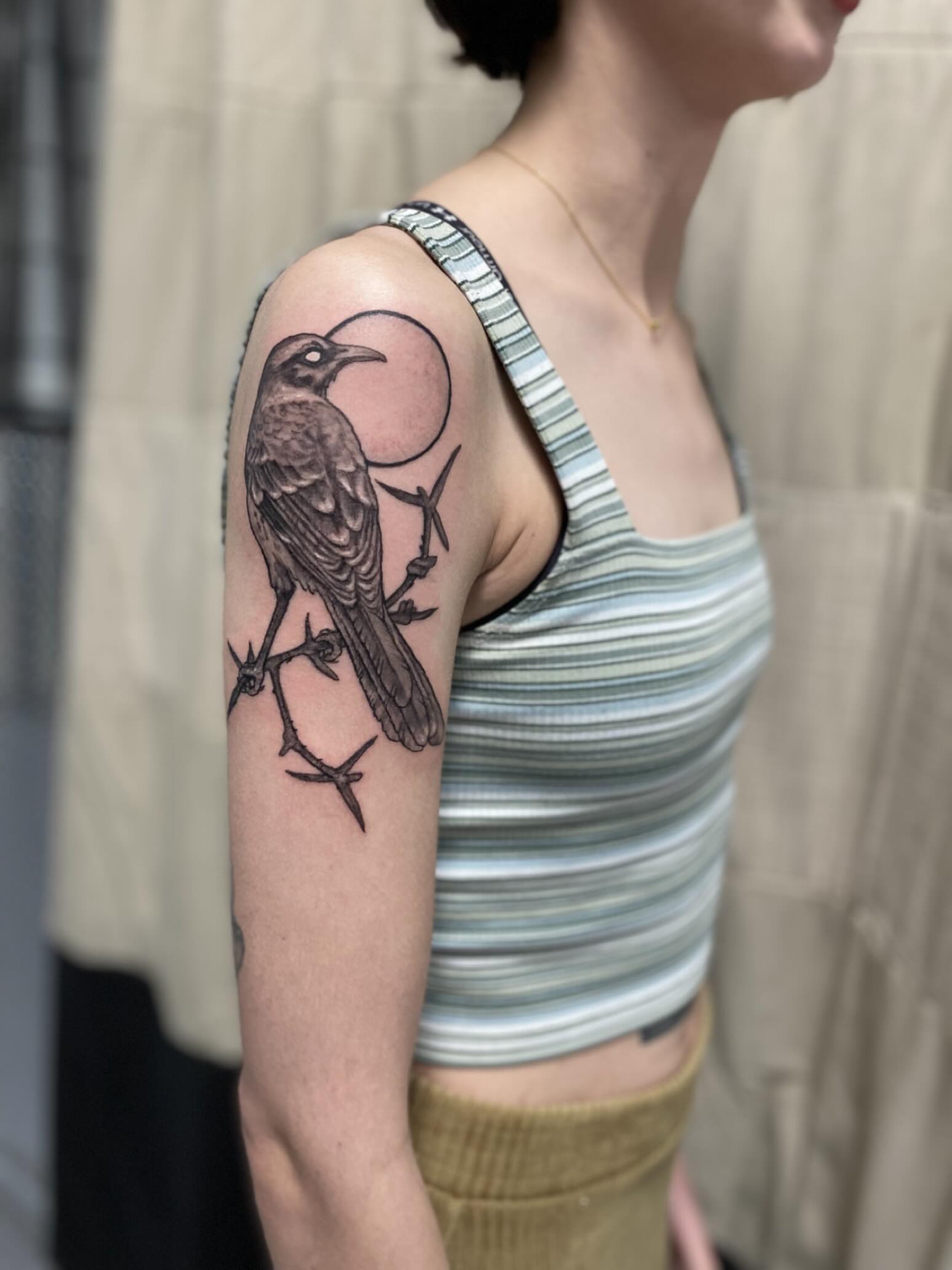 Crow and thorns black and grey tattoo on the upper arm by Dana Jones
