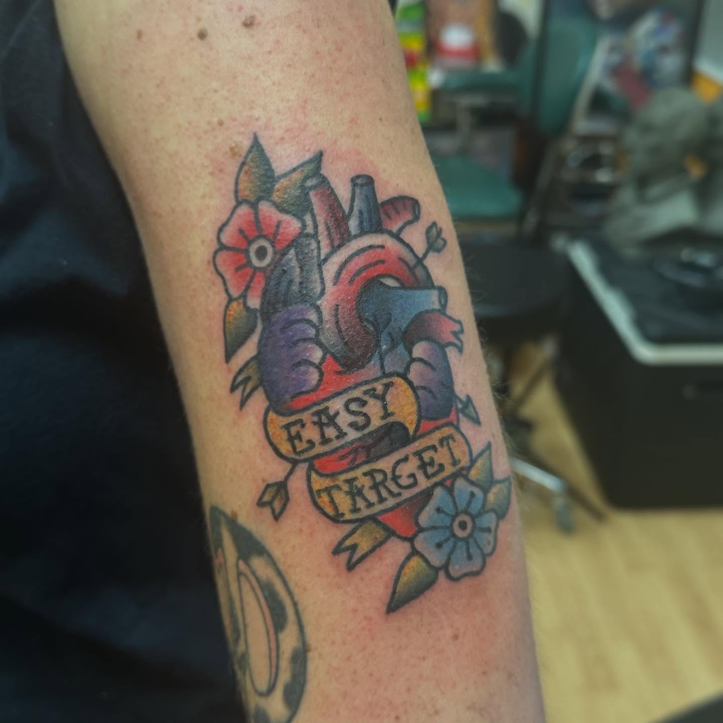 Heart with flowers American traditional tattoo on the forearm by norawillstattoo