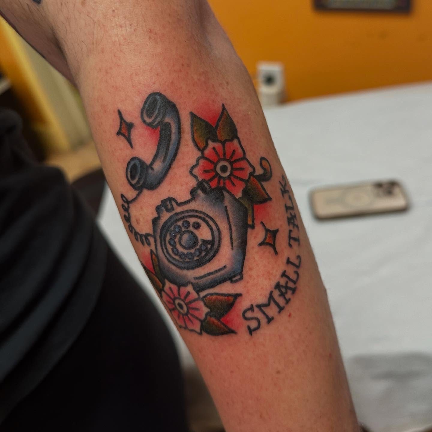 Rotary phone and flowers American traditional tattoo on the forearm by norawillstattoo