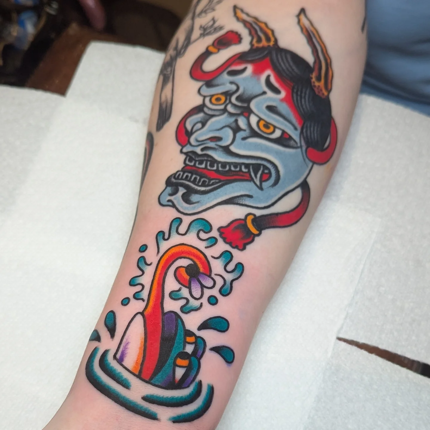 Demon mask and flower American traditional tattoo on the forearm by Zack Mueller