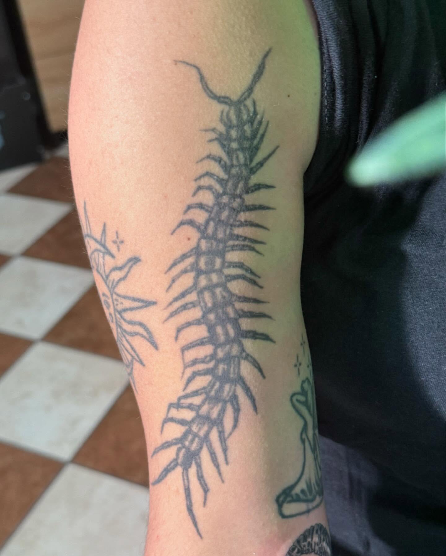 Centipede black and grey tattoo on the forearm by Nina Rush
