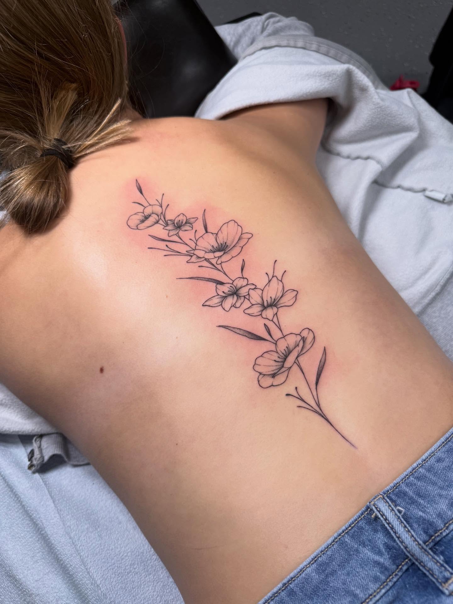Flower branch black and grey tattoo on the back by Maddie Jo DeYoung