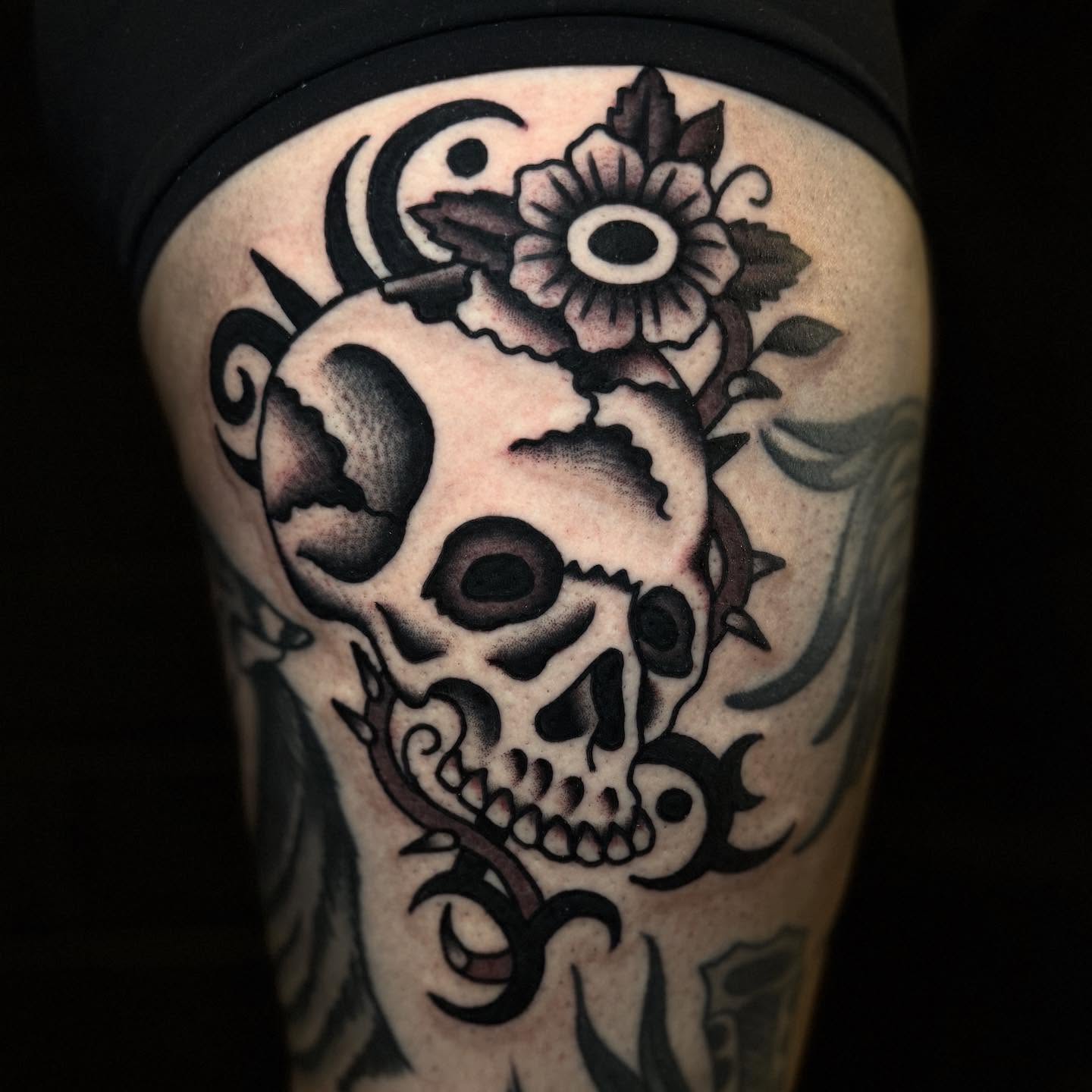 Skull and flower American traditional tattoo on the thigh by Julia Louise