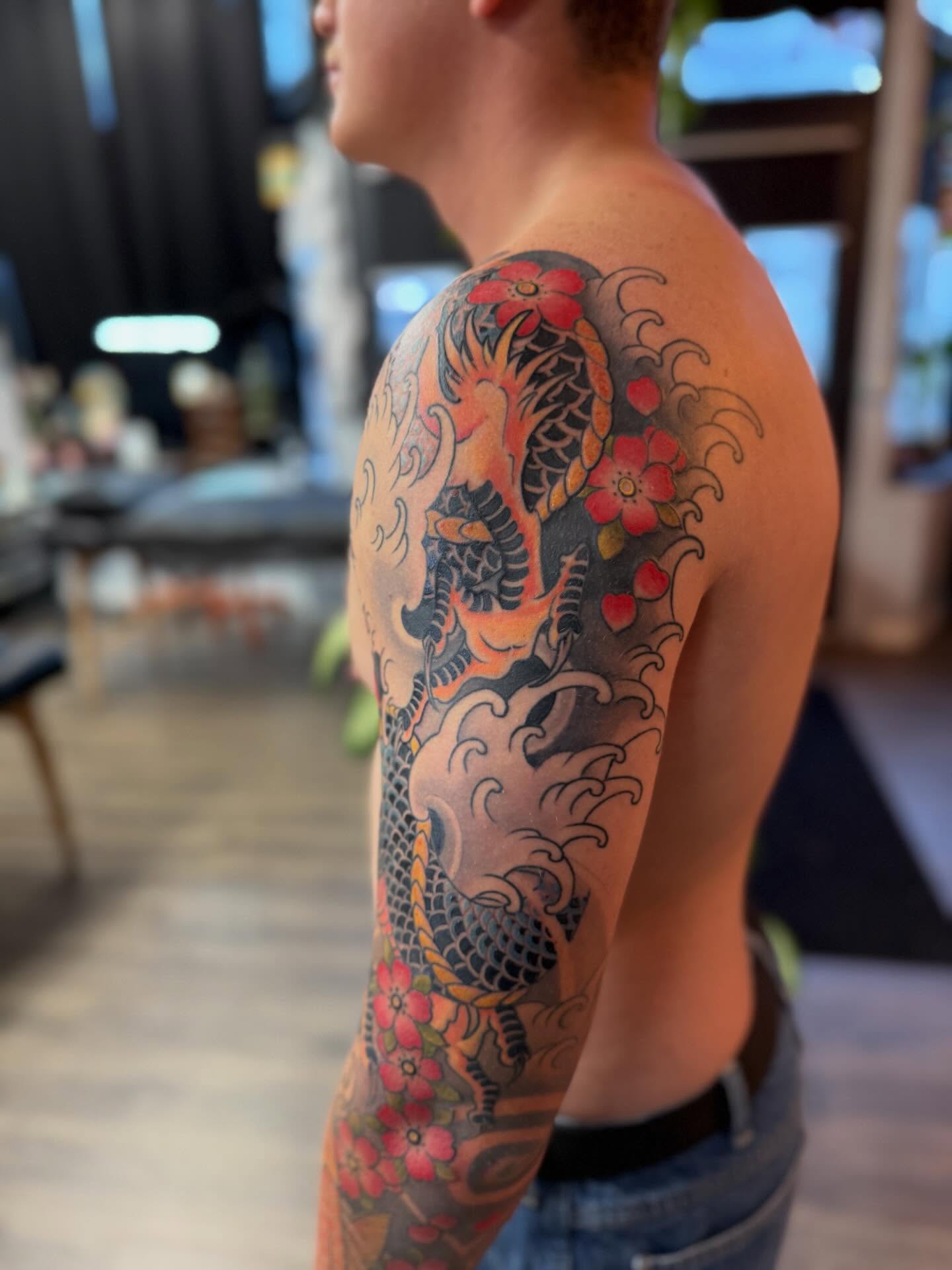 Koi fish and cherry blossoms japanese irezumi tattoo on the upper arm by Chase Martines