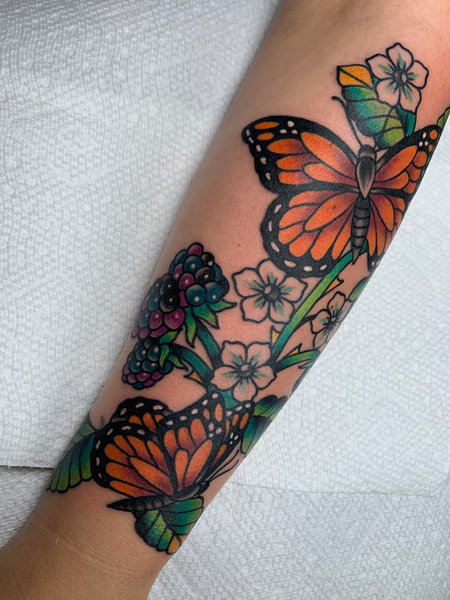 Butterfly and flowers new school tattoo on the forearm by April Morris ⚔️ Tattoo Goblin