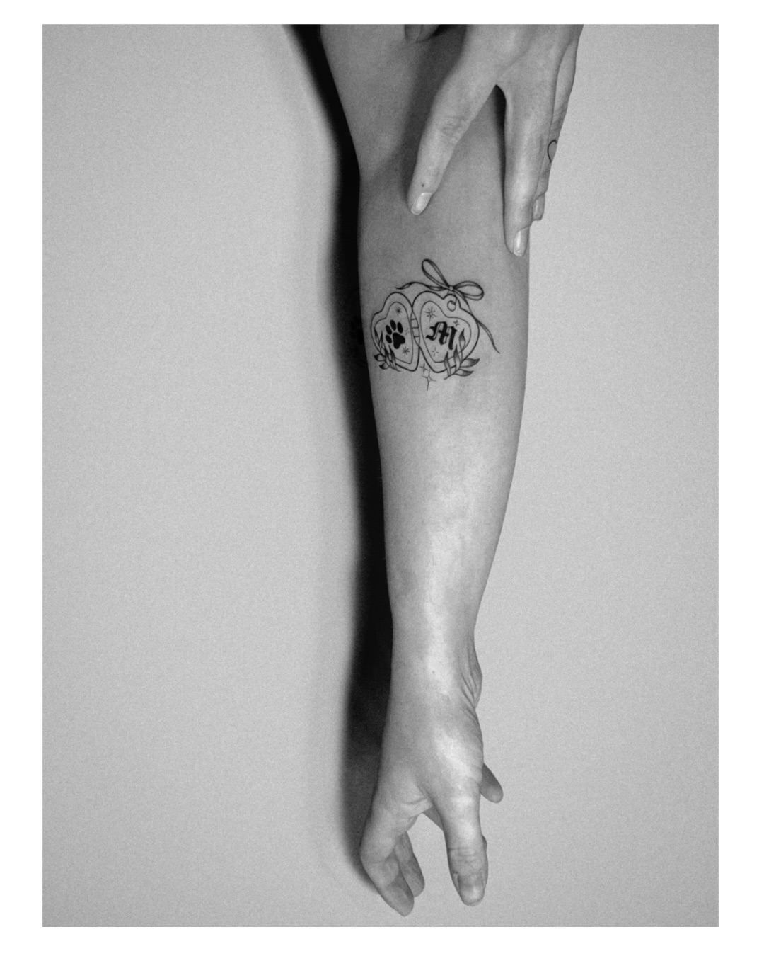 Heart and paw print black and grey tattoo on the forearm by Jordyn Tinney