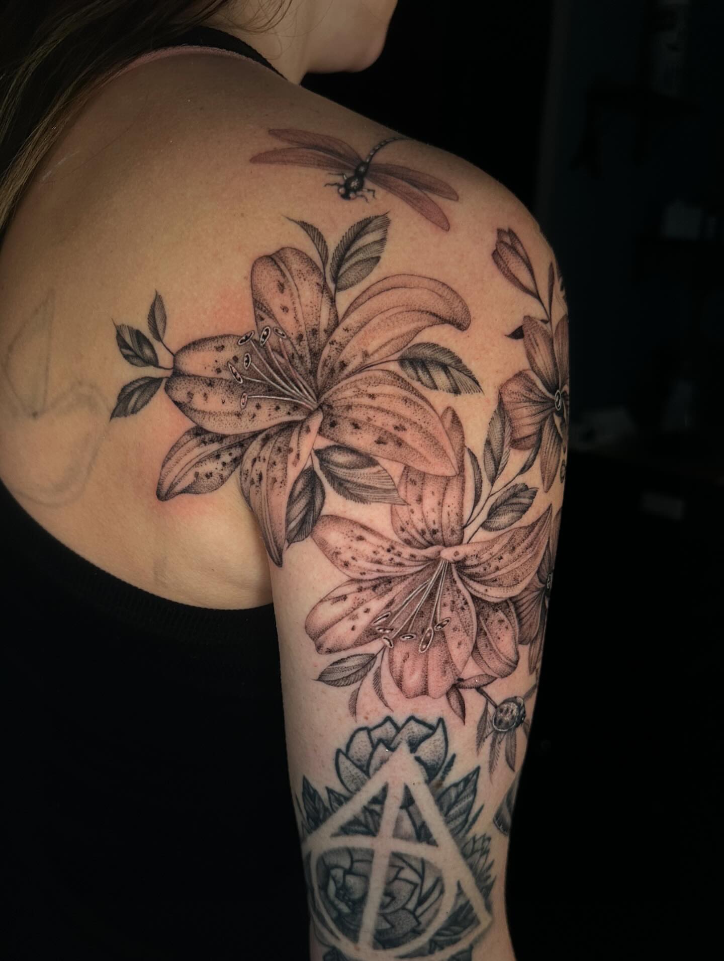 Lilies and dragonfly dotwork tattoo on the shoulder by Jhonny David lay