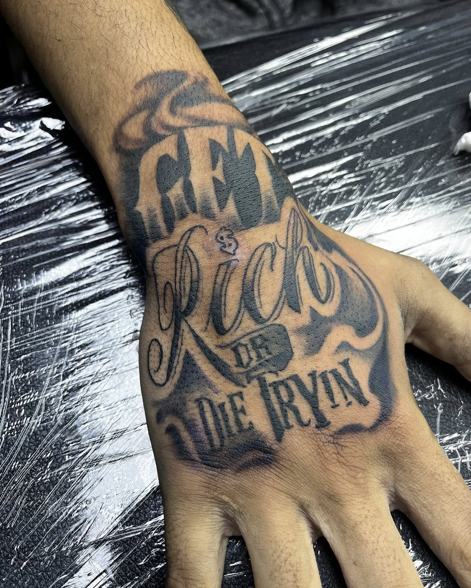 Crewm $ rich $ die tryin lettering script tattoo on the hand by Ferlandis Fitch, Long Beach, California