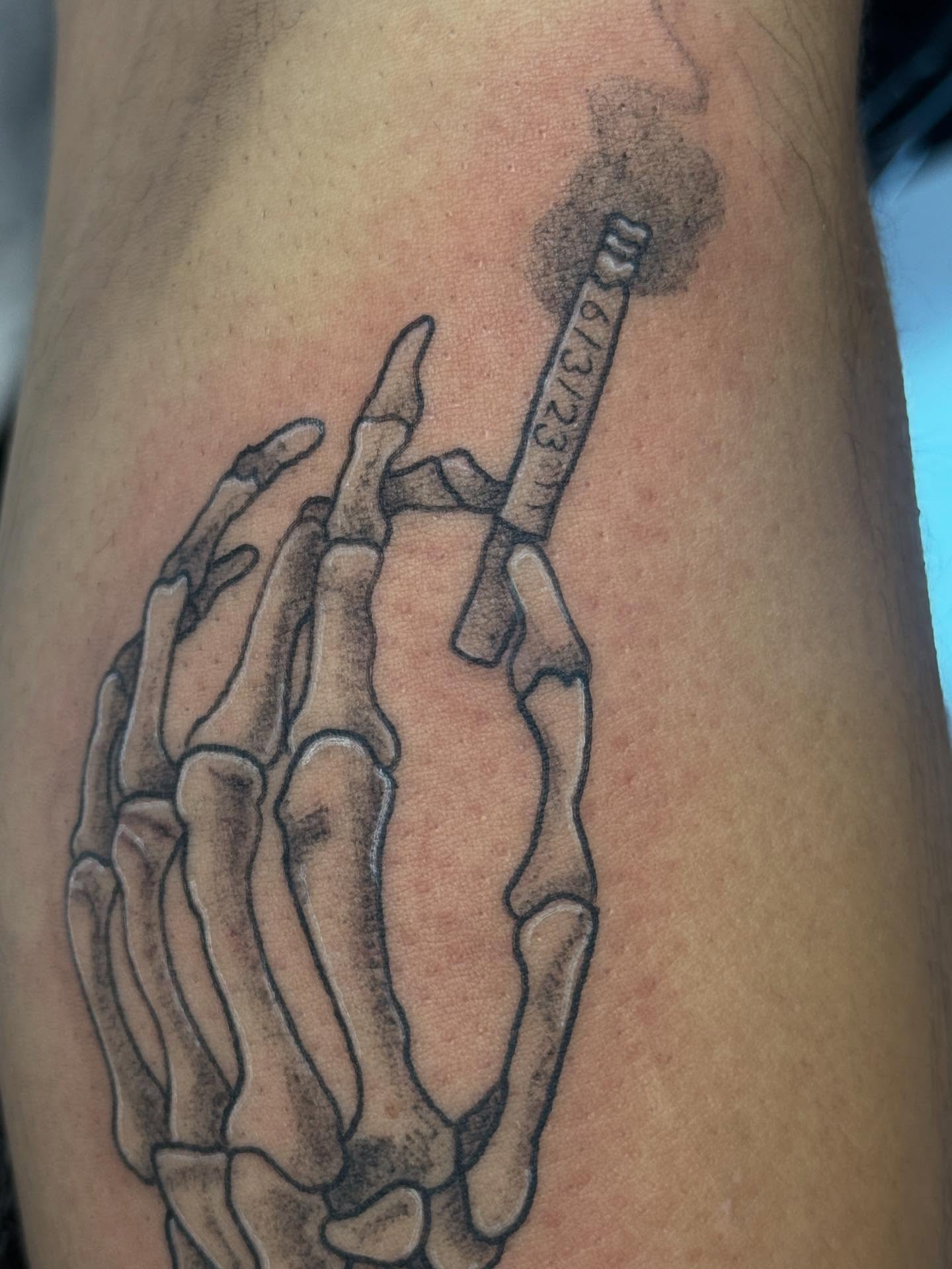 Skeleton hand holding cigarette black and grey tattoo on the forearm by goose 🪿