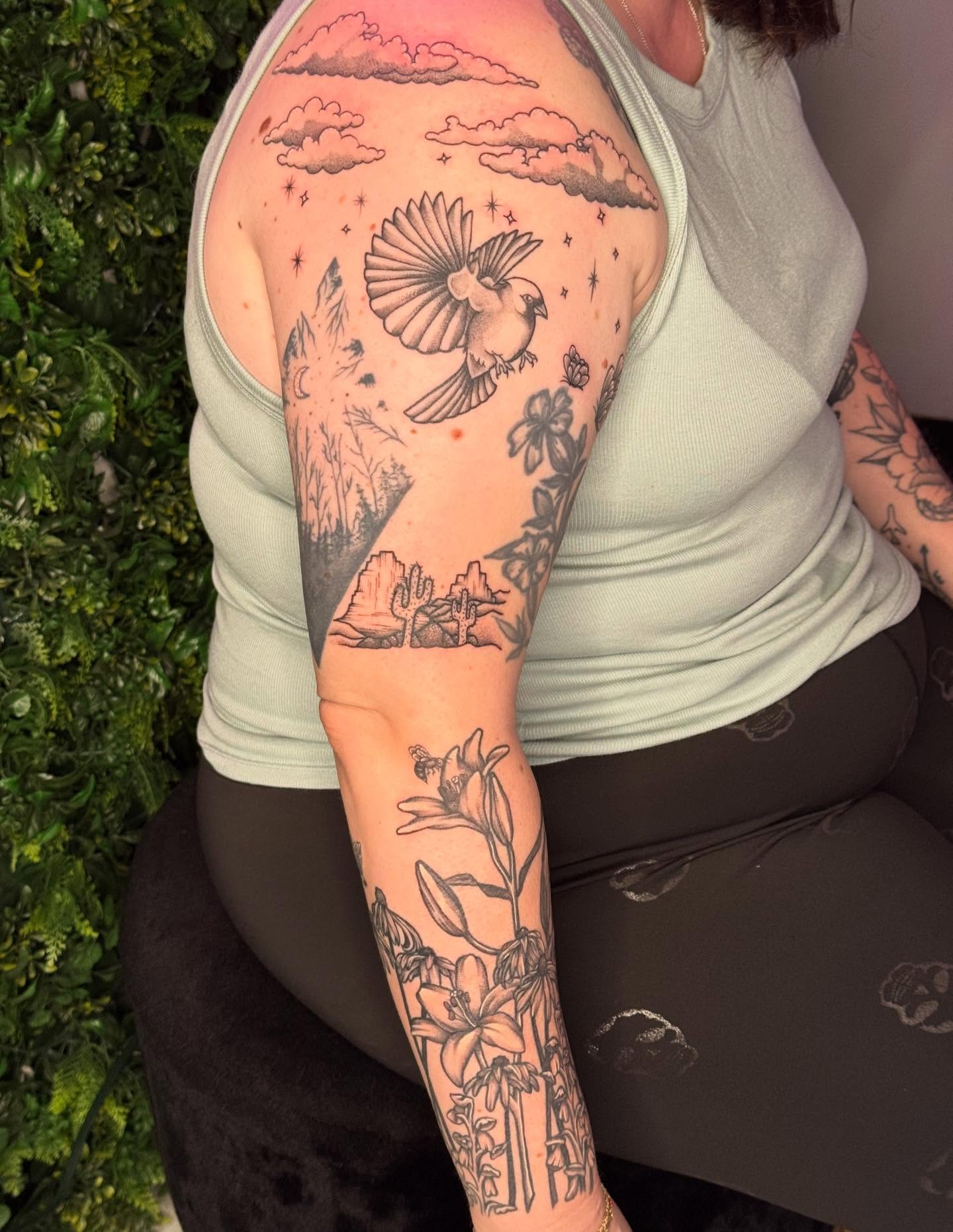 Bird and floral landscape realism tattoo on the forearm by Ember