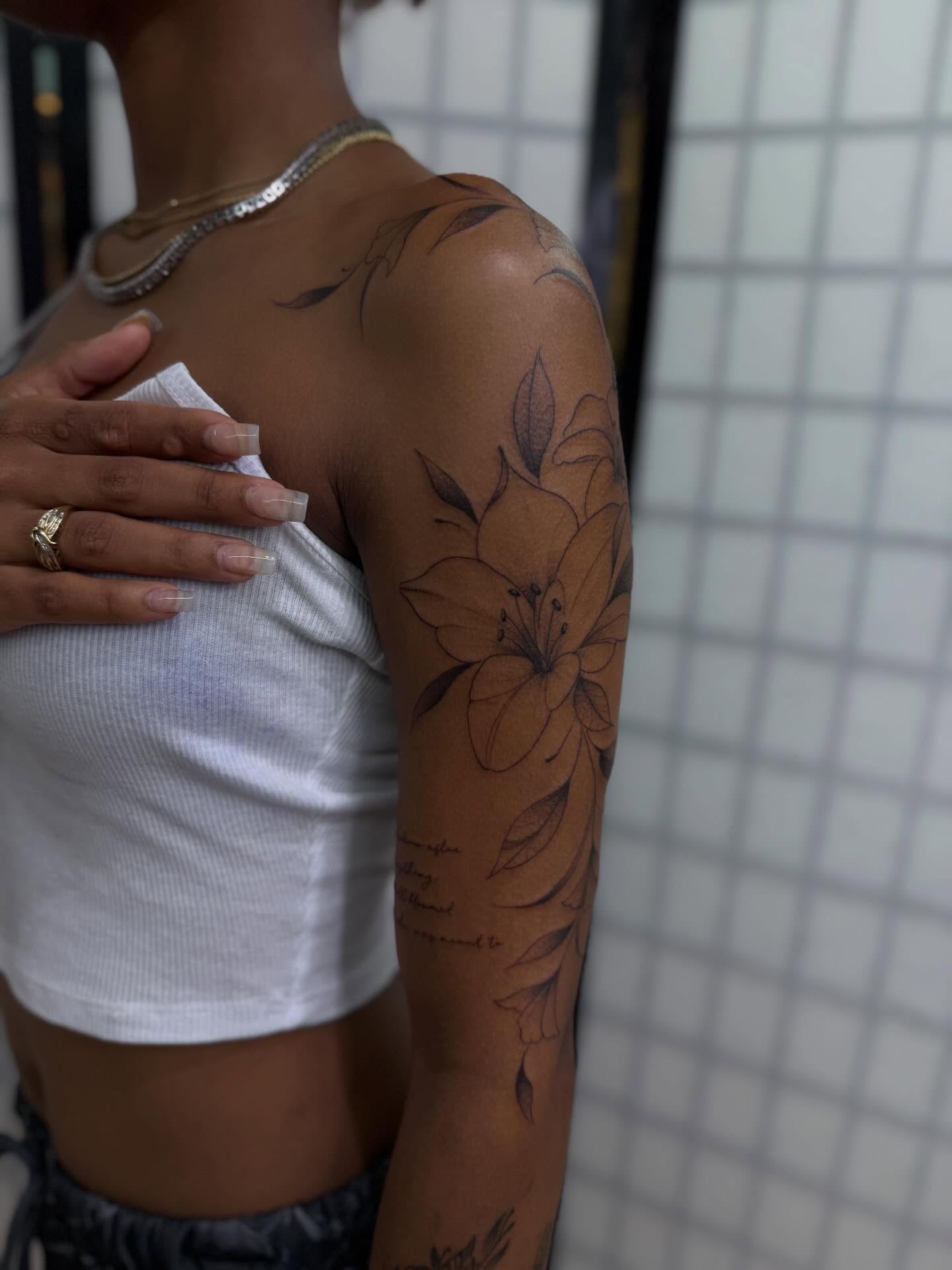 Lily black and grey tattoo on the upper arm by christian martinez