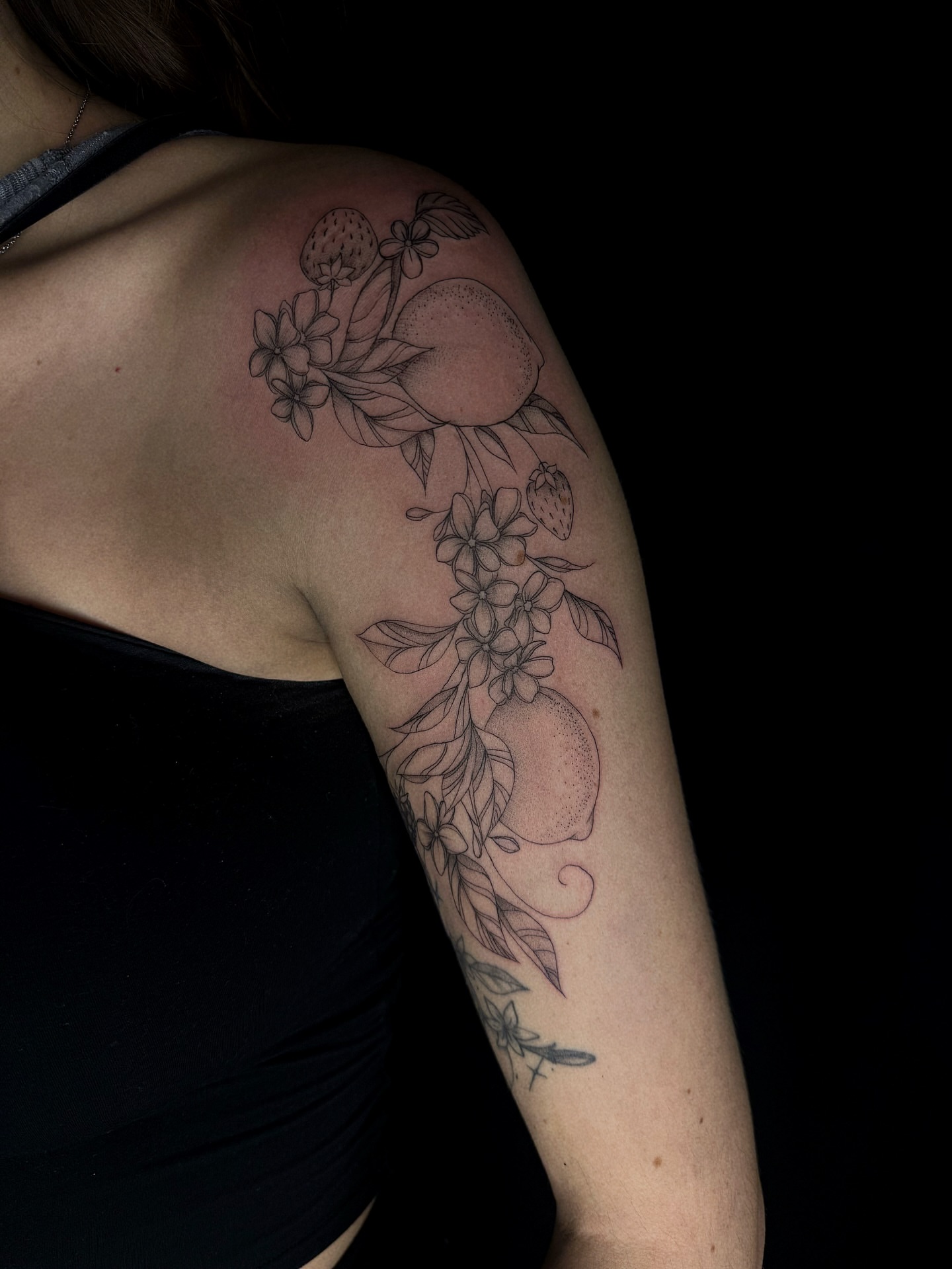 Fruit and floral arrangement black and grey tattoo on the shoulder by elena