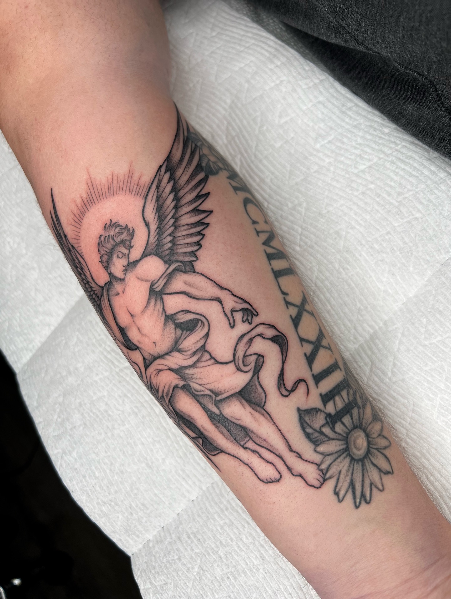Cherub and sun black and grey tattoo on the forearm by 𝔐𝔦𝔠𝔥𝔢𝔩𝔩𝔢 ℭ𝔥𝔞𝔪𝔢𝔯𝔩𝔦𝔨