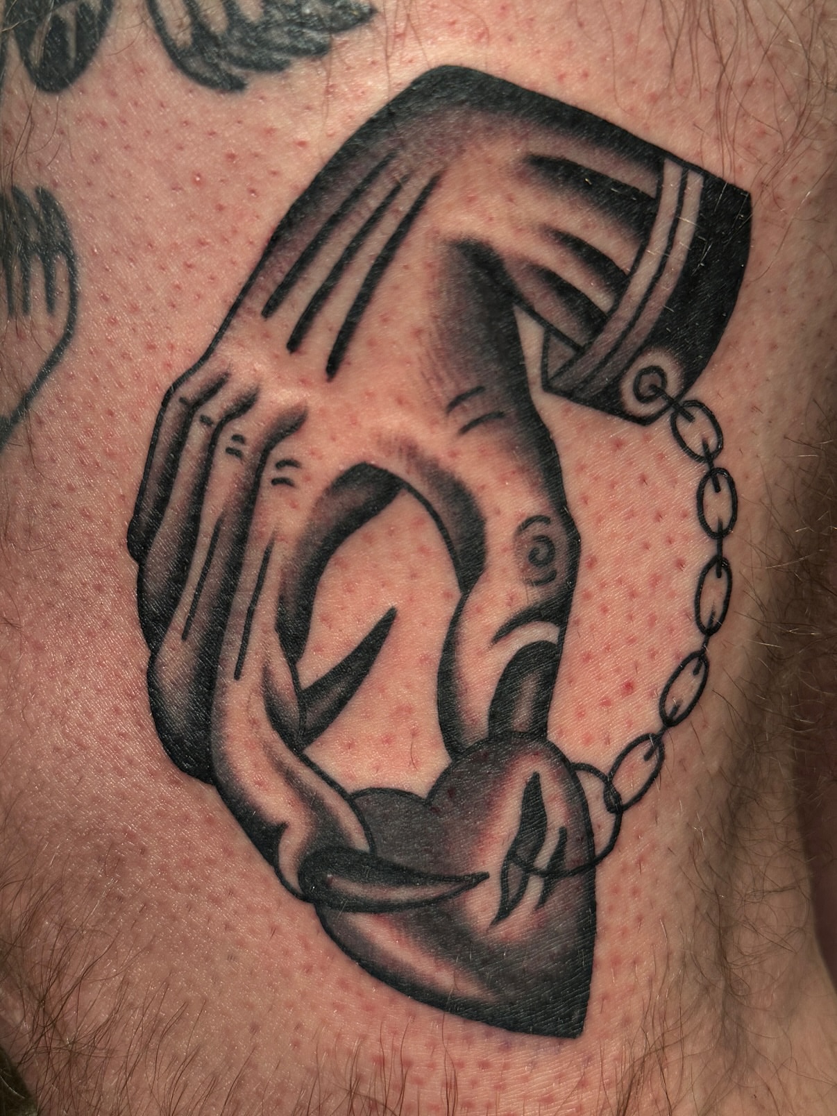 Hand holding chain black and grey tattoo on the thigh by Chaz Otto
