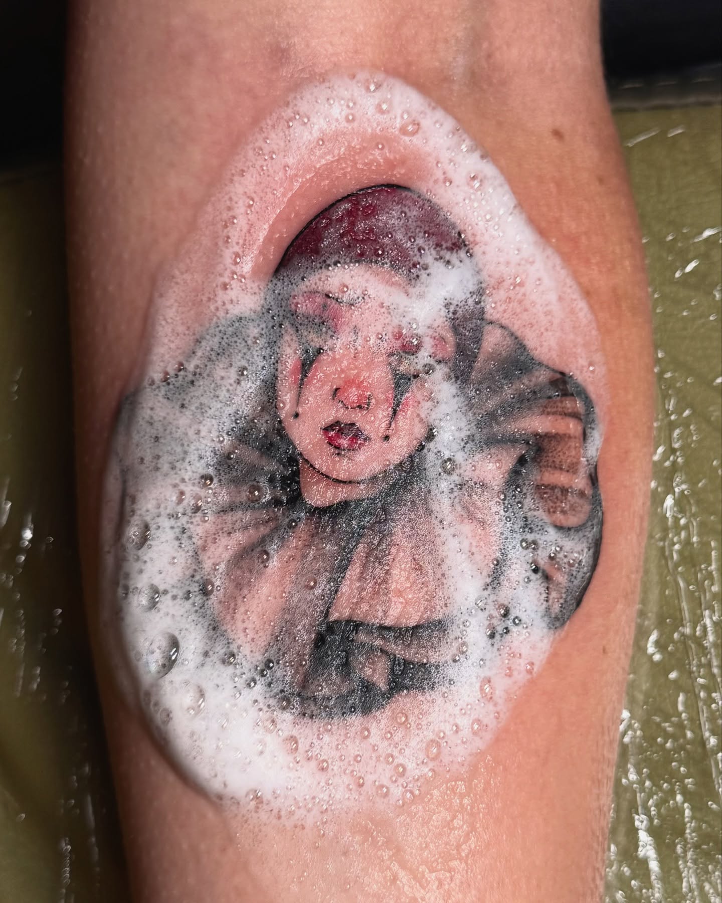 Child in bubble bath realism tattoo on the forearm by laura baldwin