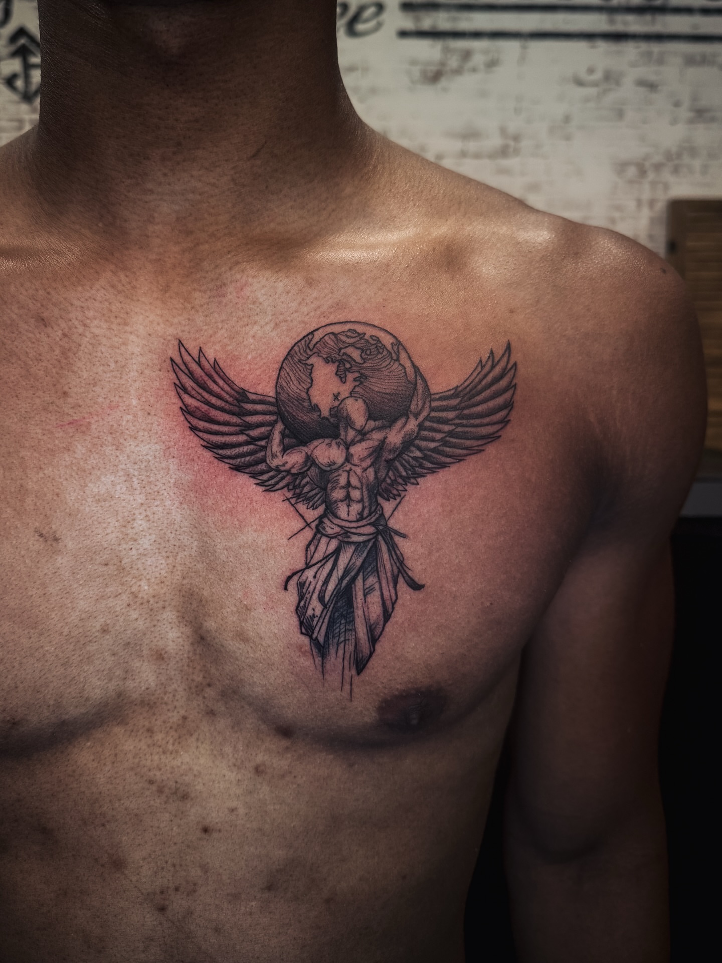Winged figure black and grey tattoo on the chest by Brandt Norcross